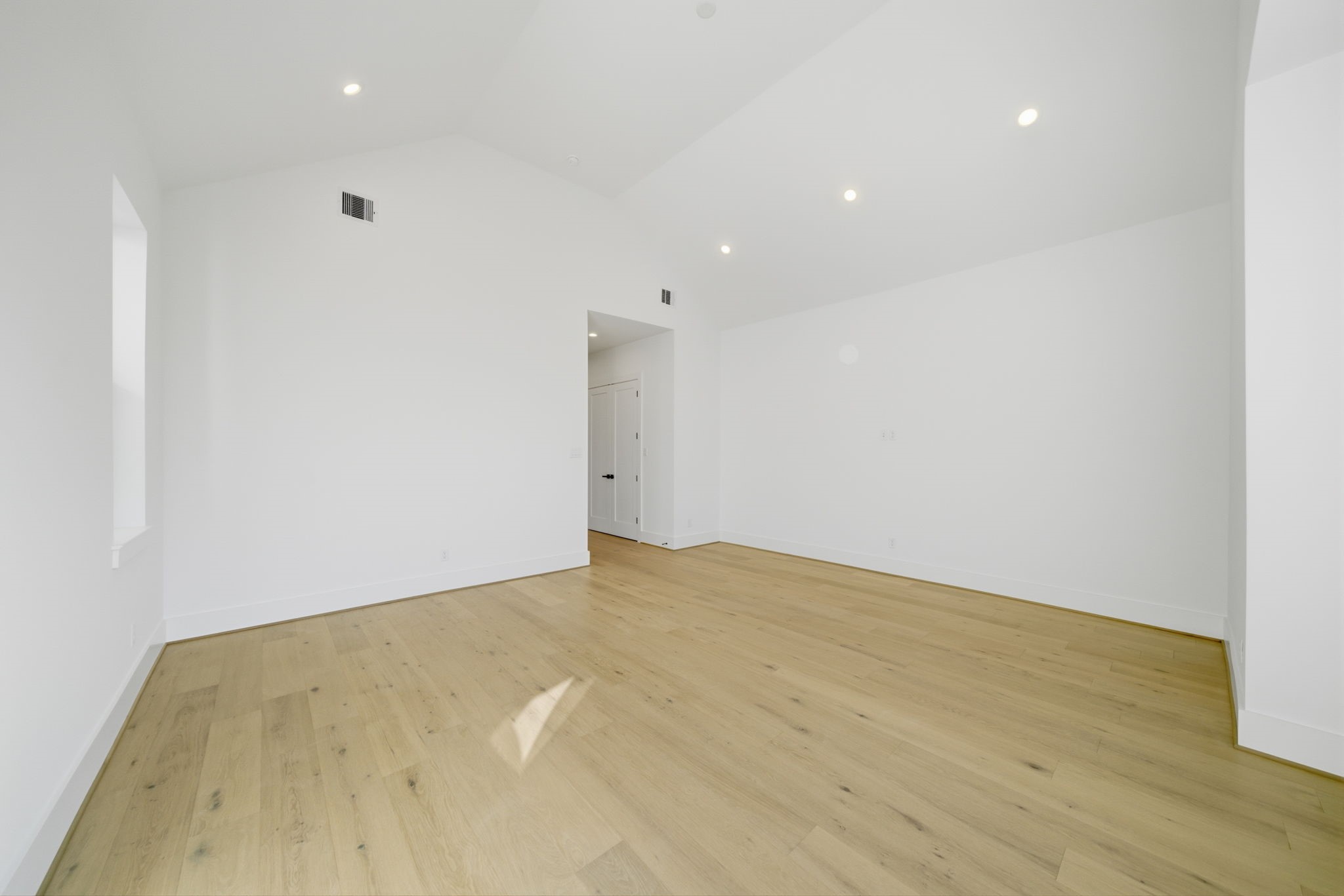Alternate view of the spacious primary bedroom with beautiful wood flooring. (Photos are of a previously completed home. Finishes are subject to change.)
