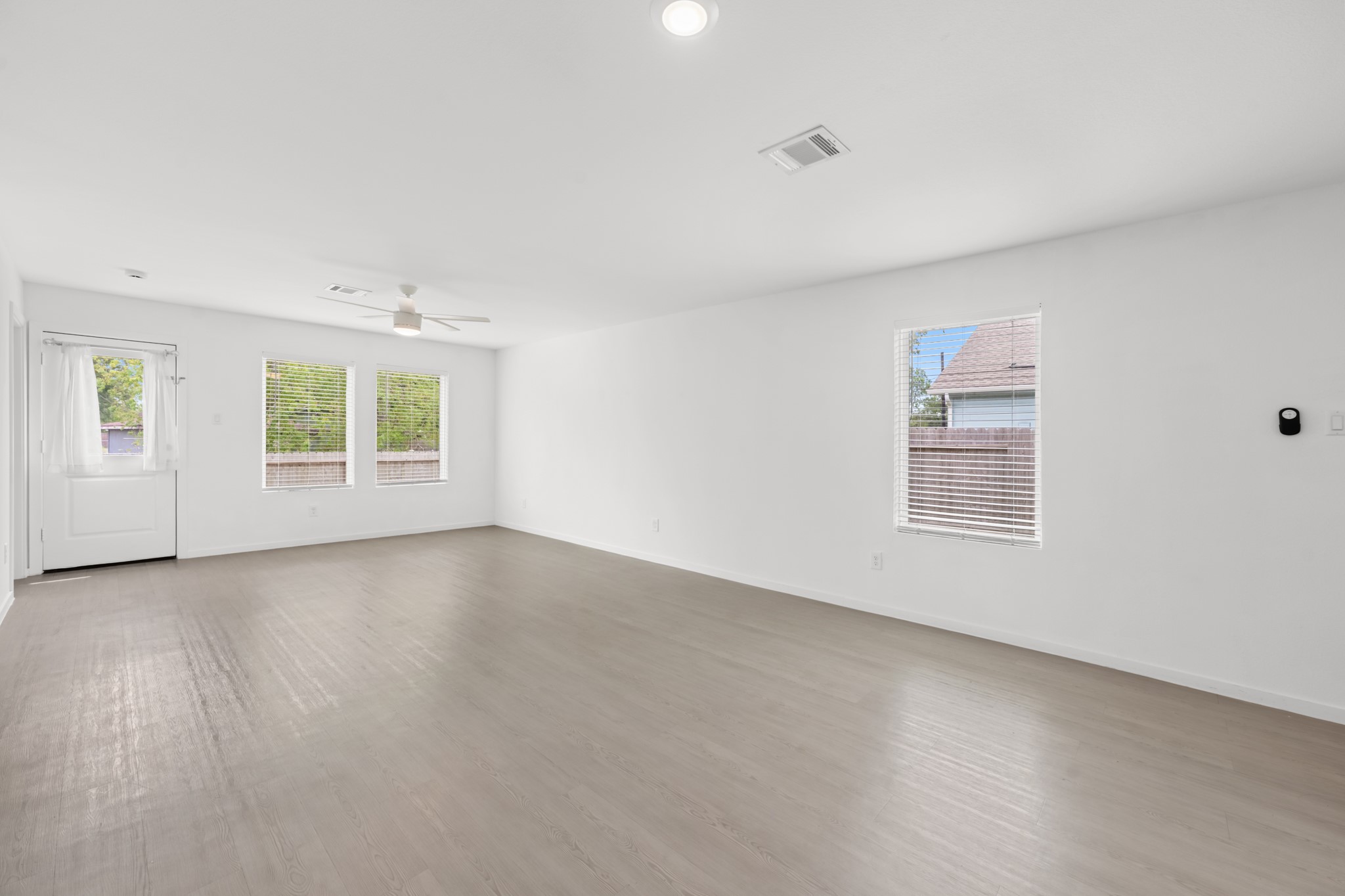 Multiple windows brighten the open living area, while the neutral color palette and continuous flooring create a clean, cohesive look.