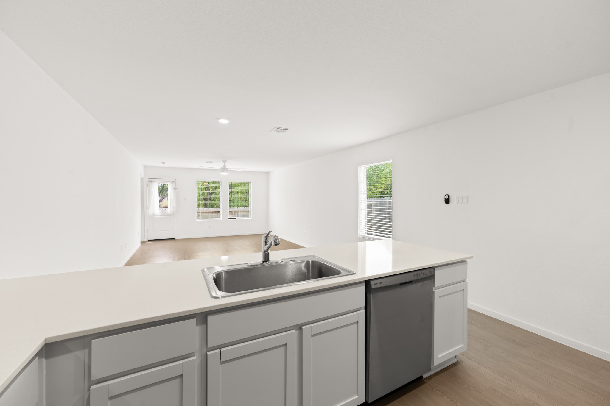 View from the kitchen showcases the open layout extending into the living area, with a generous peninsula, coordinated flooring, and multiple windows bringing in natural light.