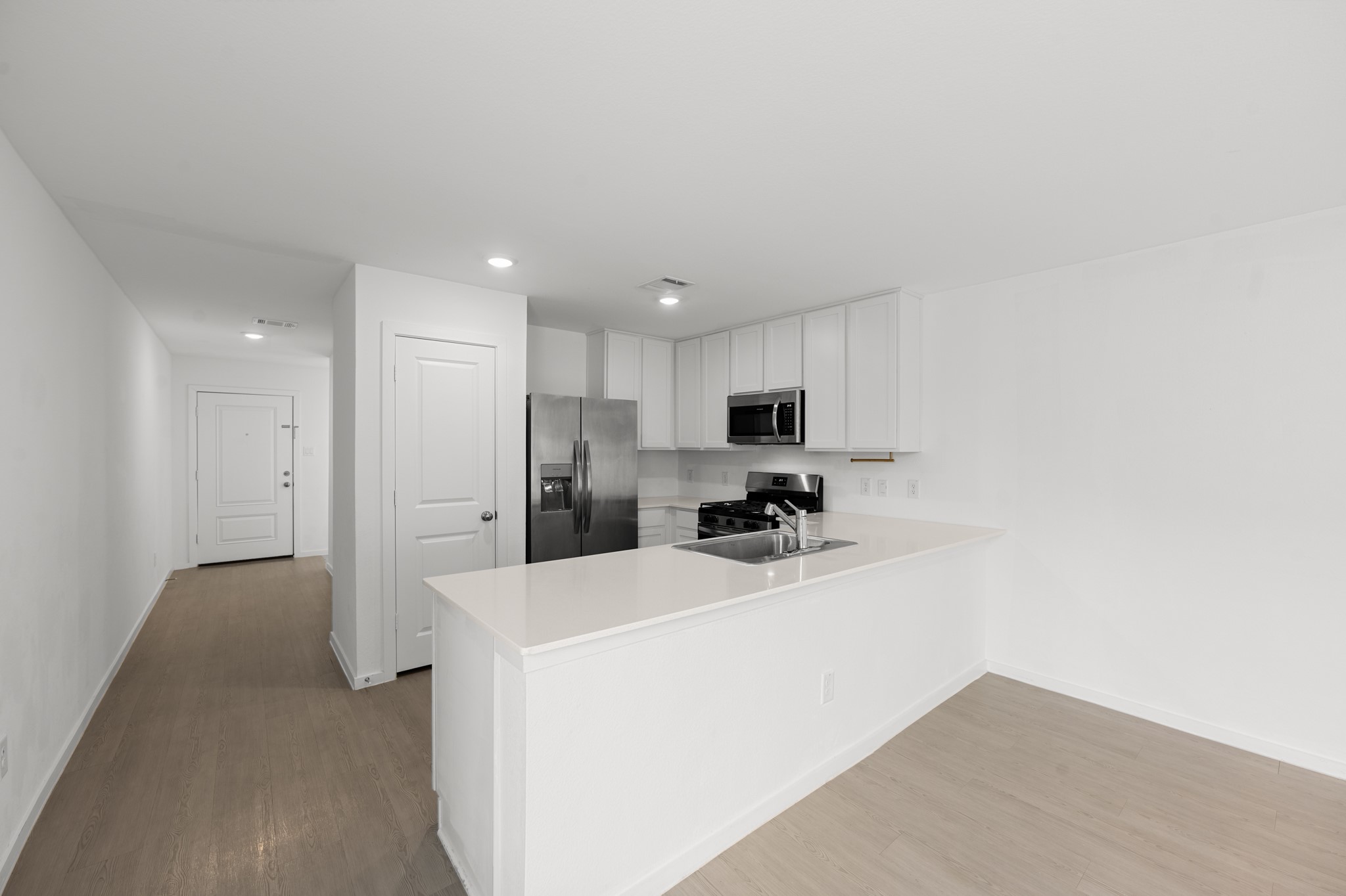 A wide peninsula opens the kitchen to the adjoining dining area, creating an easy flow for everyday meals and entertaining. Light-toned flooring and neutral finishes carry throughout the space.