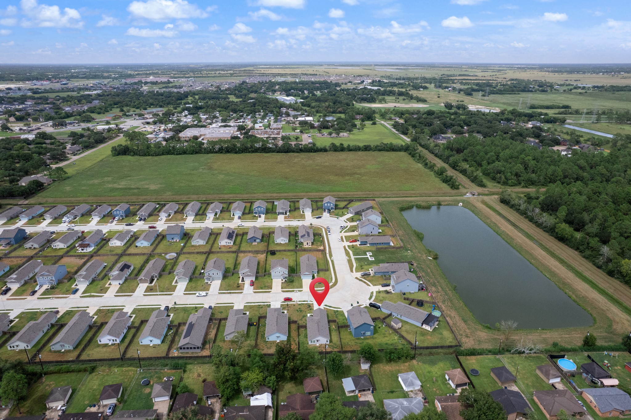 Elevated perspective highlights the homes location within the residential development, with a nearby pond and surrounding open areas visible.