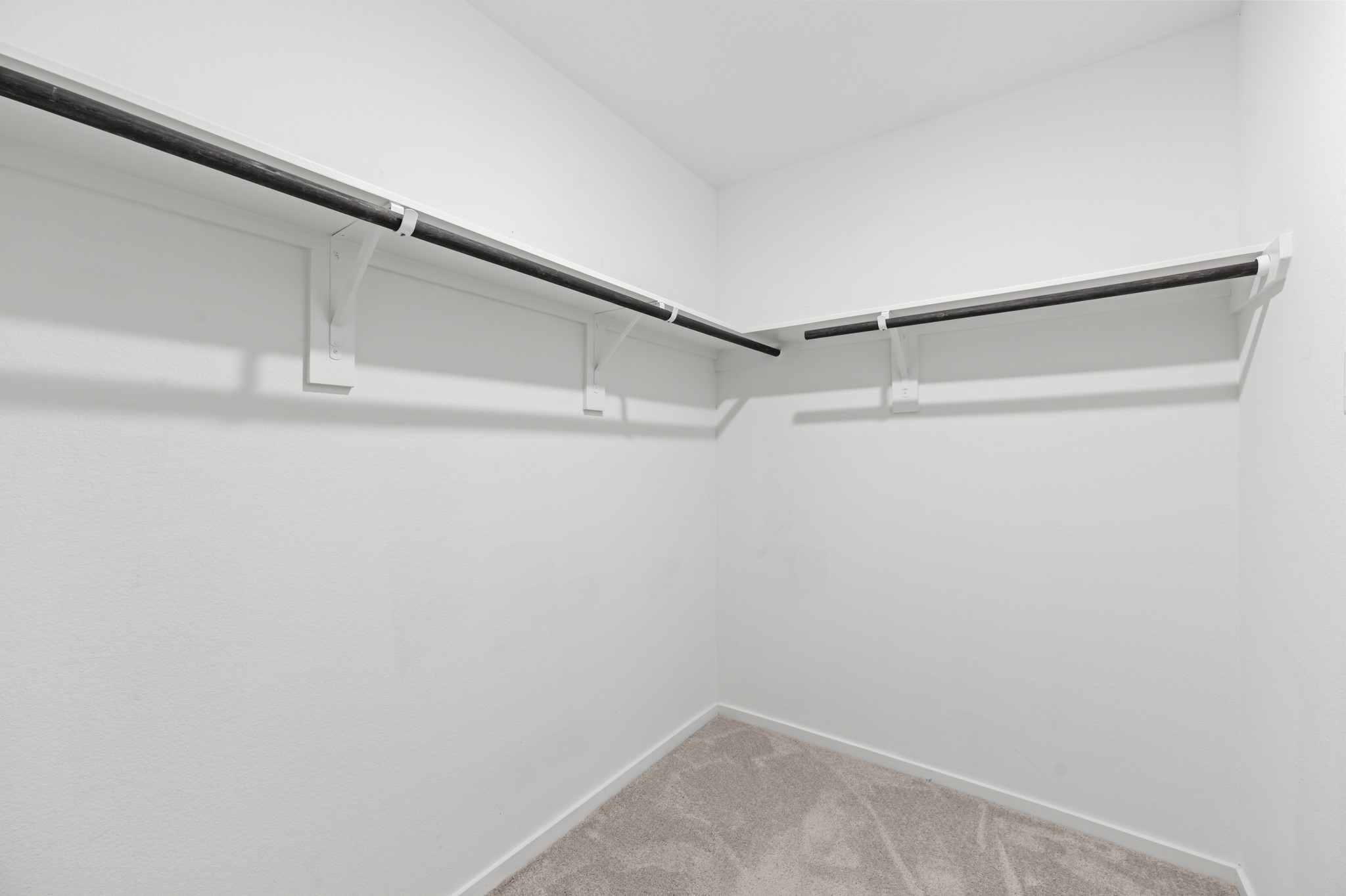 Generously sized walk-in closet offers wraparound hanging rods and shelving for organized wardrobe storage.