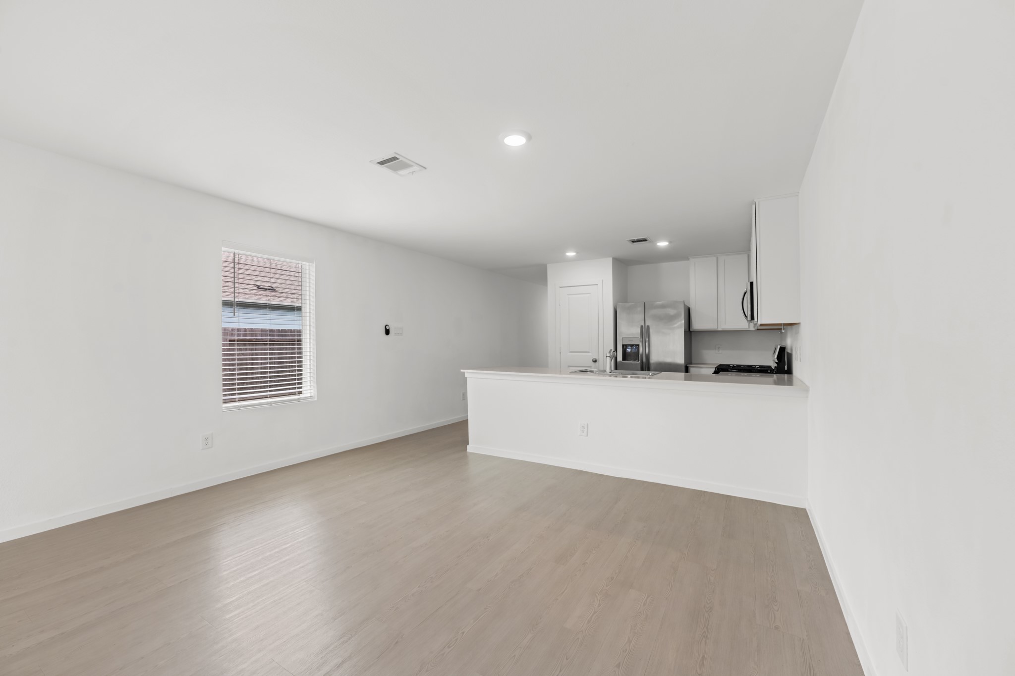 Flexible dining area sits adjacent to the kitchen peninsula, with a nearby window adding natural light and plenty of open wall space for furniture placement.