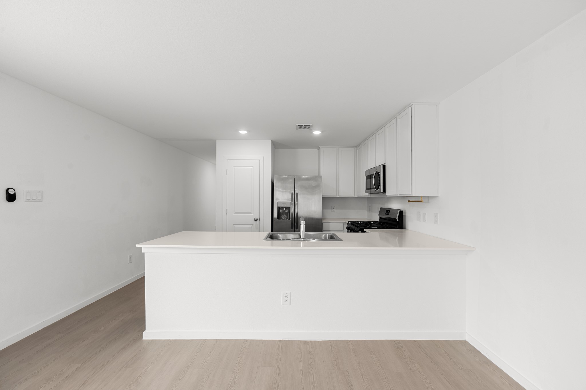 Expansive peninsula provides ample prep and serving space while keeping the kitchen visually connected to the surrounding living areas. Crisp white cabinetry pairs with stainless steel appliances for a streamlined finish.