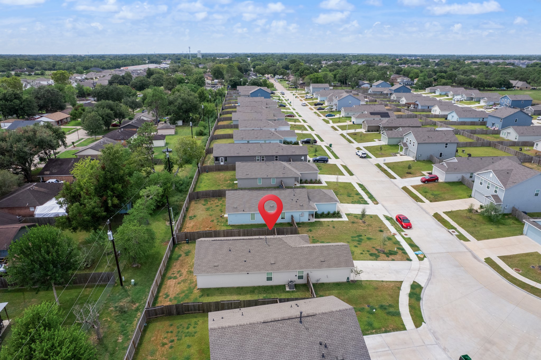 Closer aerial perspective highlights the property and its fenced backyard while showing the surrounding streets and neighboring homes.