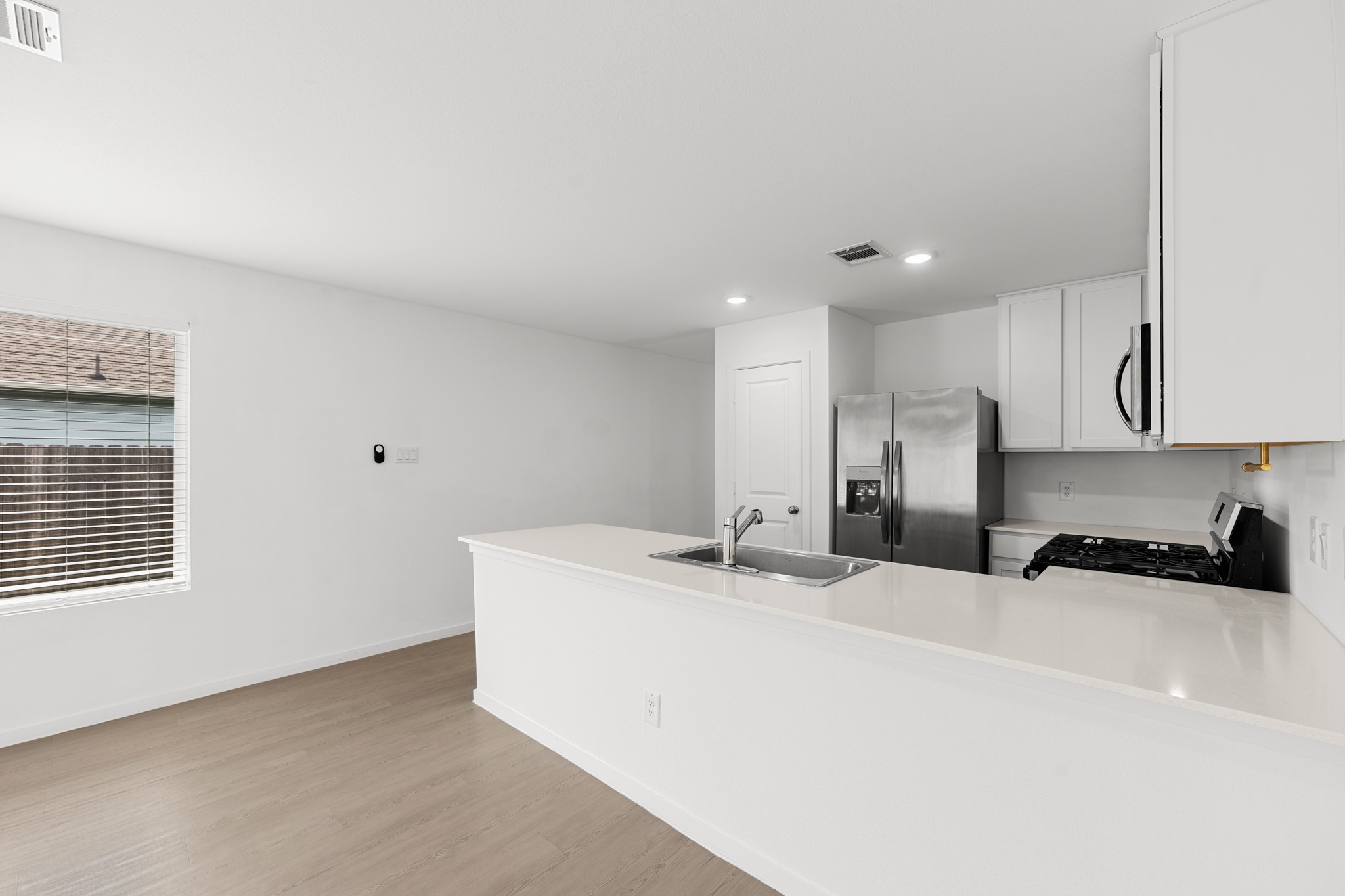 Kitchen & Dining Area  Bright kitchen features a spacious peninsula with an integrated sink and generous counter space, opening to an adjacent dining area with a large window for natural light.
