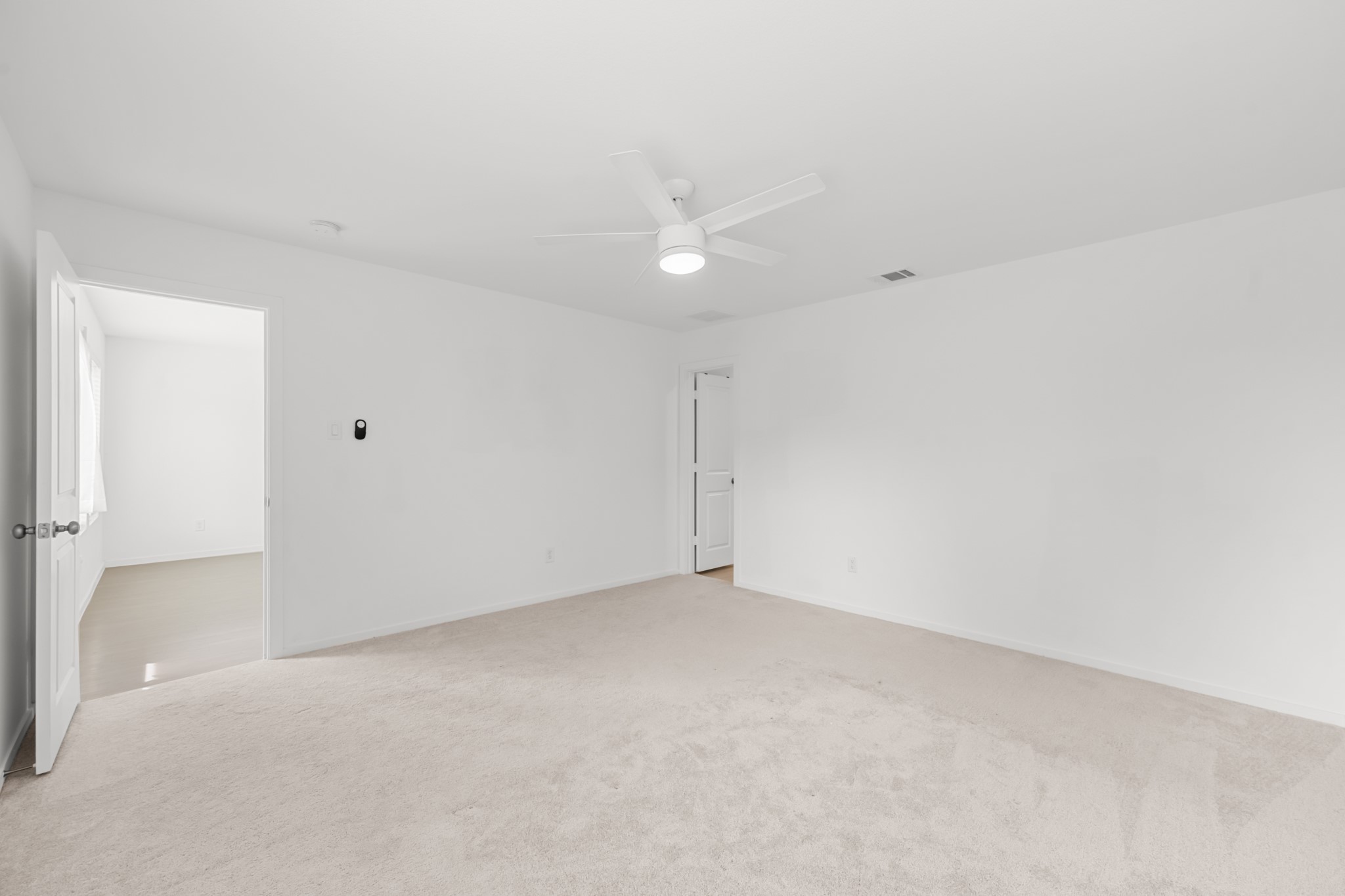 Additional view of the primary bedroom showcases its generous proportions and direct connection to the adjoining spaces.