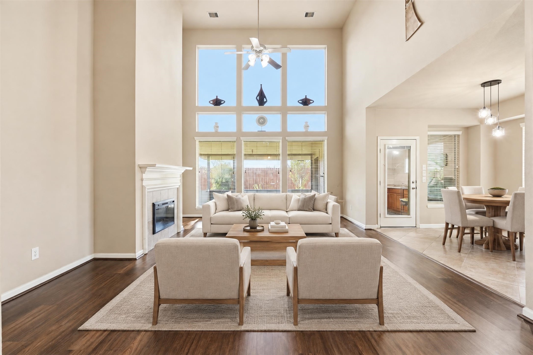 Virtually staged. The two-story living room is the showpiece: a full wall of windows floods the space with natural light, and the fireplace gives the room a cozy anchor.
