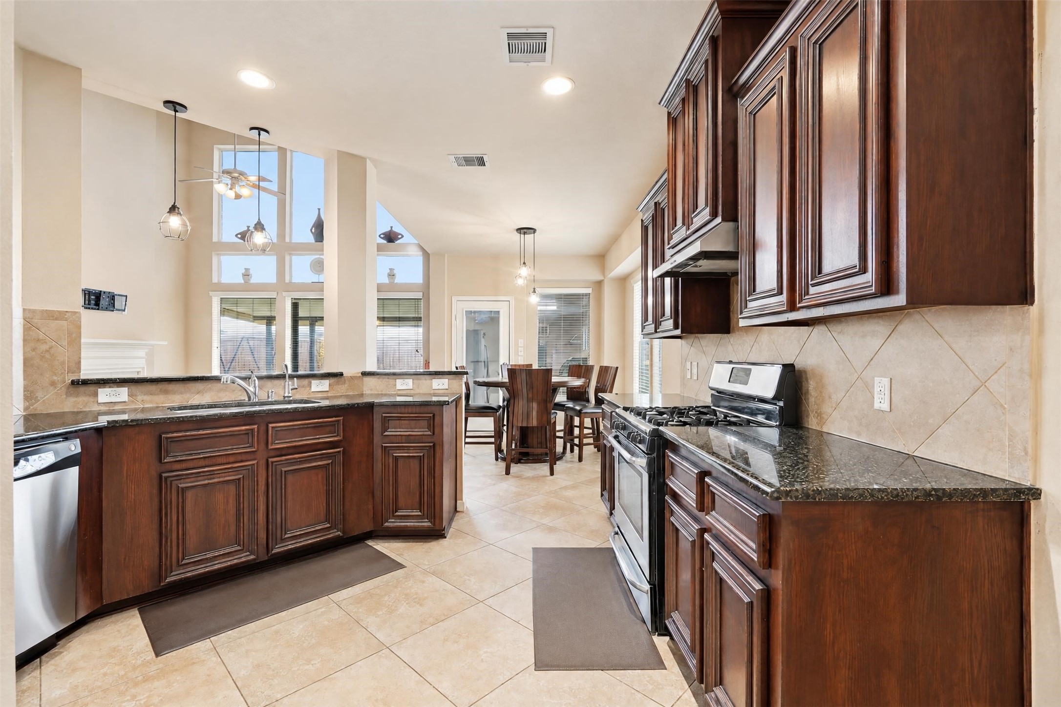 The kitchen is set up for real cooking: rich wood cabinetry, granite counters, stainless appliances and a gas range, all open to the breakfast area and living room so the cook is never left out.