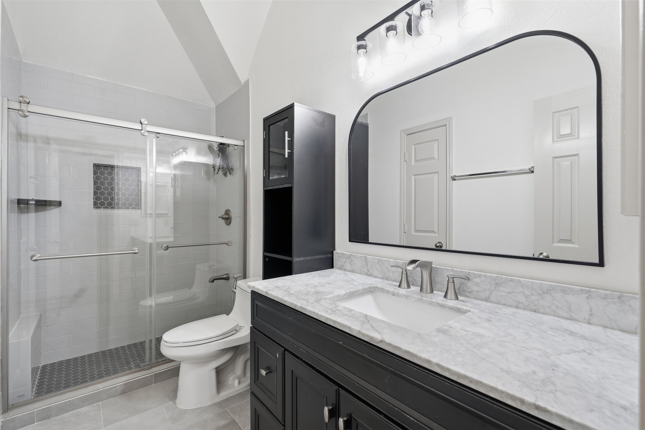 Updated bathroom with marble-look counters, a matte black vanity, a statement mirror and a glass-enclosed shower.