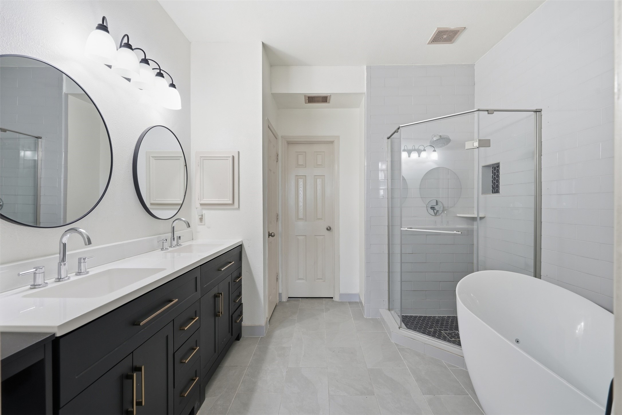 The remodeled primary bath feels like a retreat: a double vanity, a freestanding soaking tub and a walk-in glass shower.