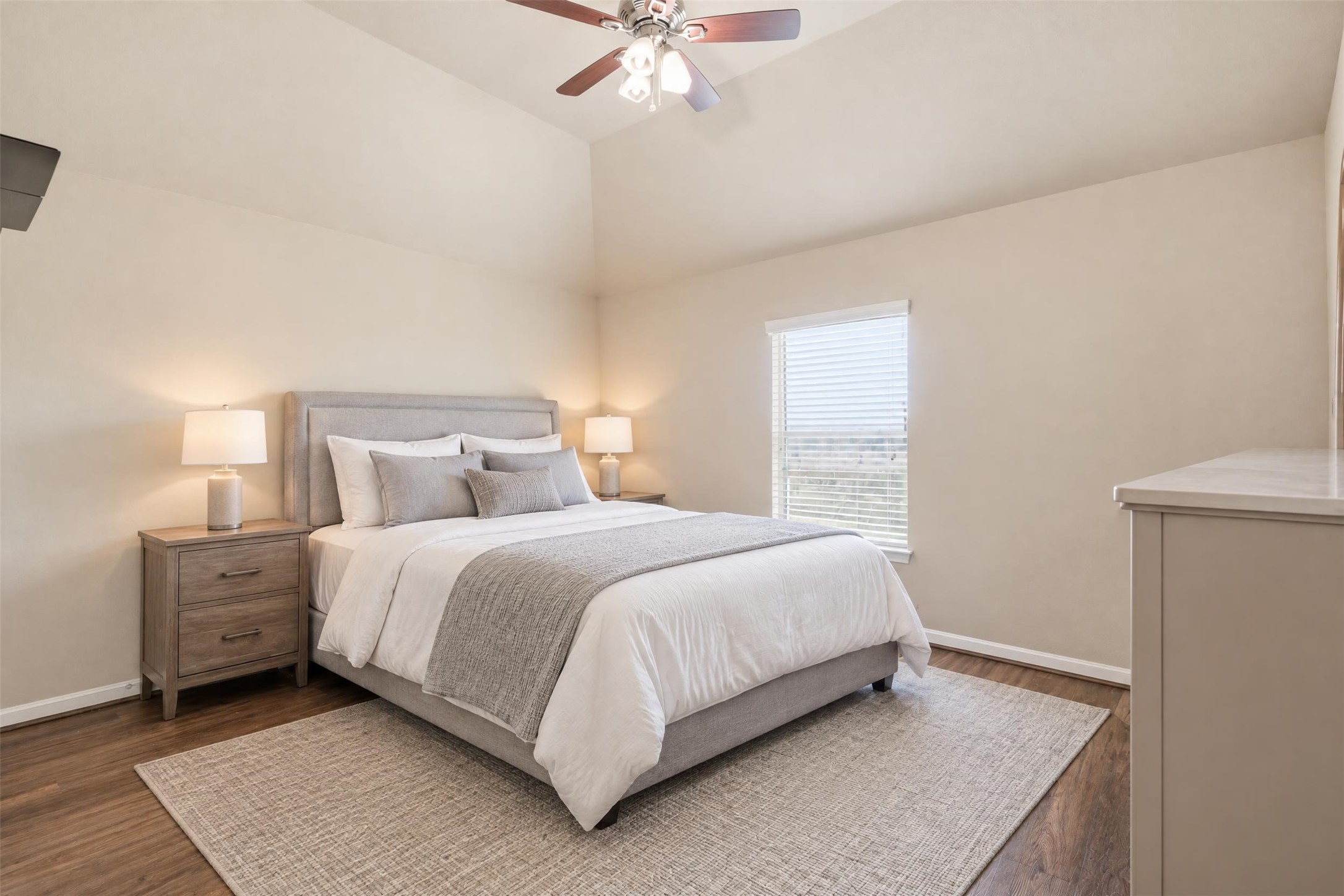 Virtually staged. Secondary bedroom with a vaulted ceiling and lots of natural light, with room for a queen bed and a desk.