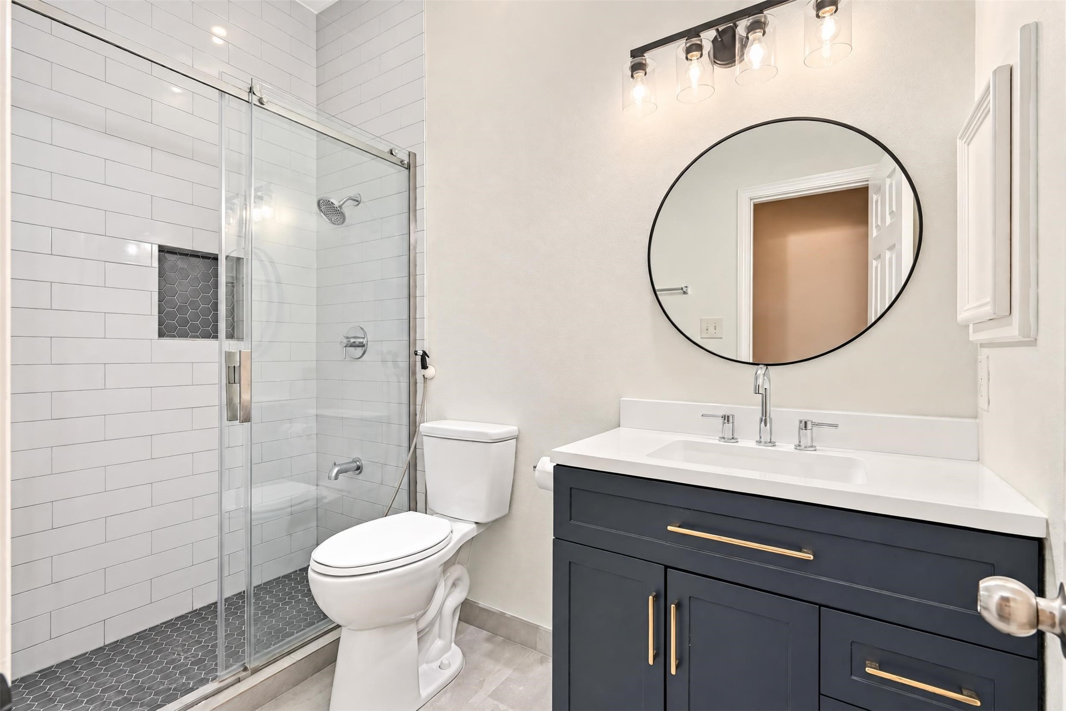 Updated bathroom with a subway-tile walk-in shower behind clear glass and a clean modern vanity.