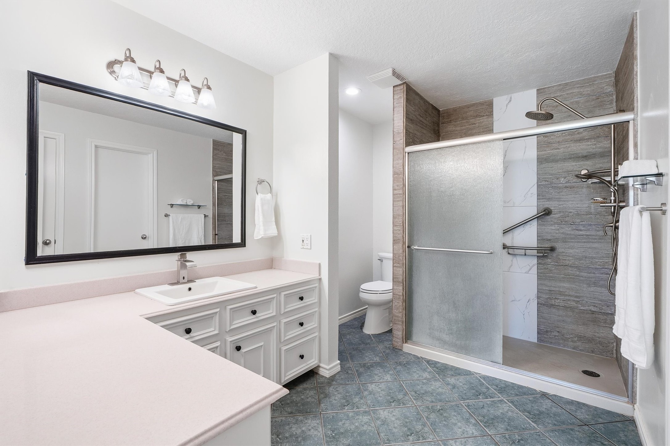 The extra-large walk-in shower steals the show here, with frosted shower door, finished with built-in grab bars and a rainfall showerhead for a spa-style routine every morning.