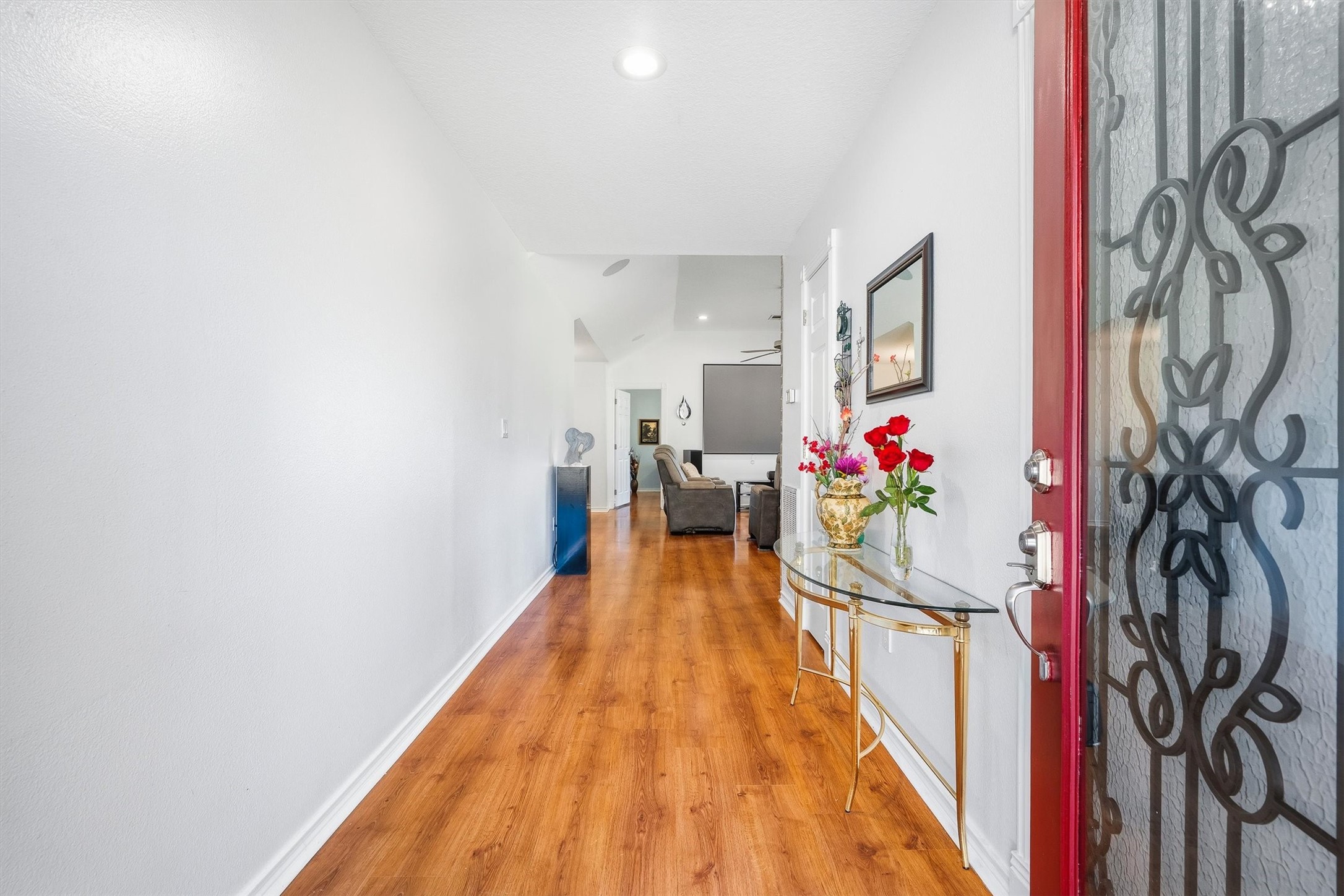 The foyer sets the tone with warm wood-look laminate floors and bright white walls that lead you straight back toward the main living space.