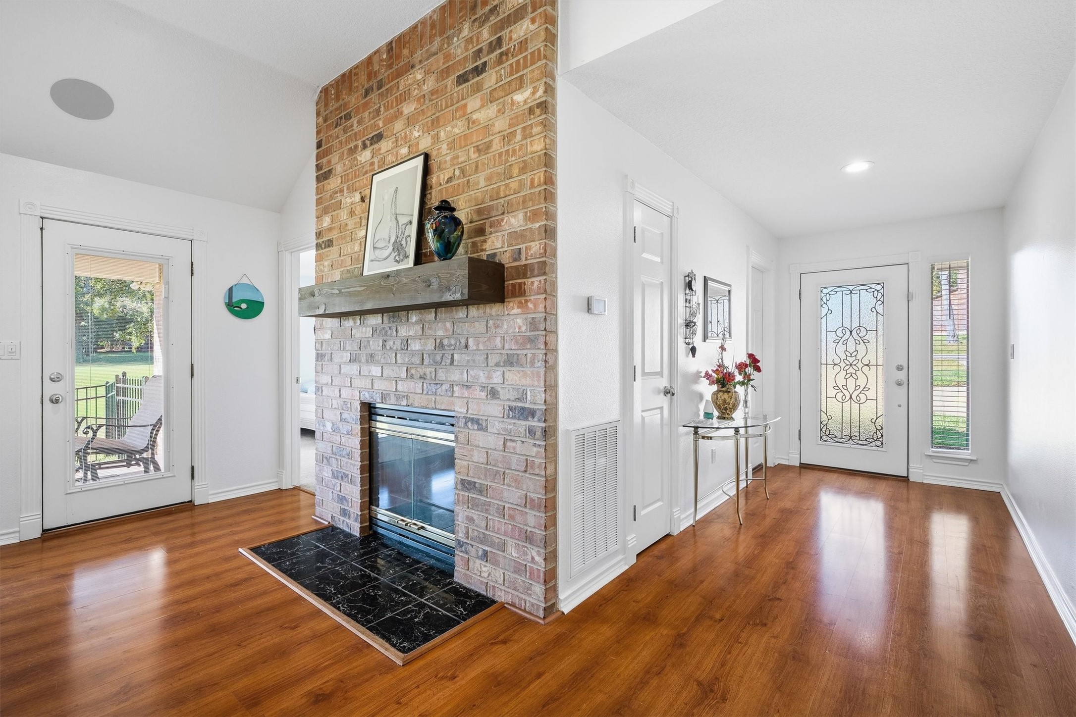 A floor-to-ceiling brick fireplace with a rustic wood mantel anchors the room, ready for cozy nights whenever a Texas cold front decides to show up.