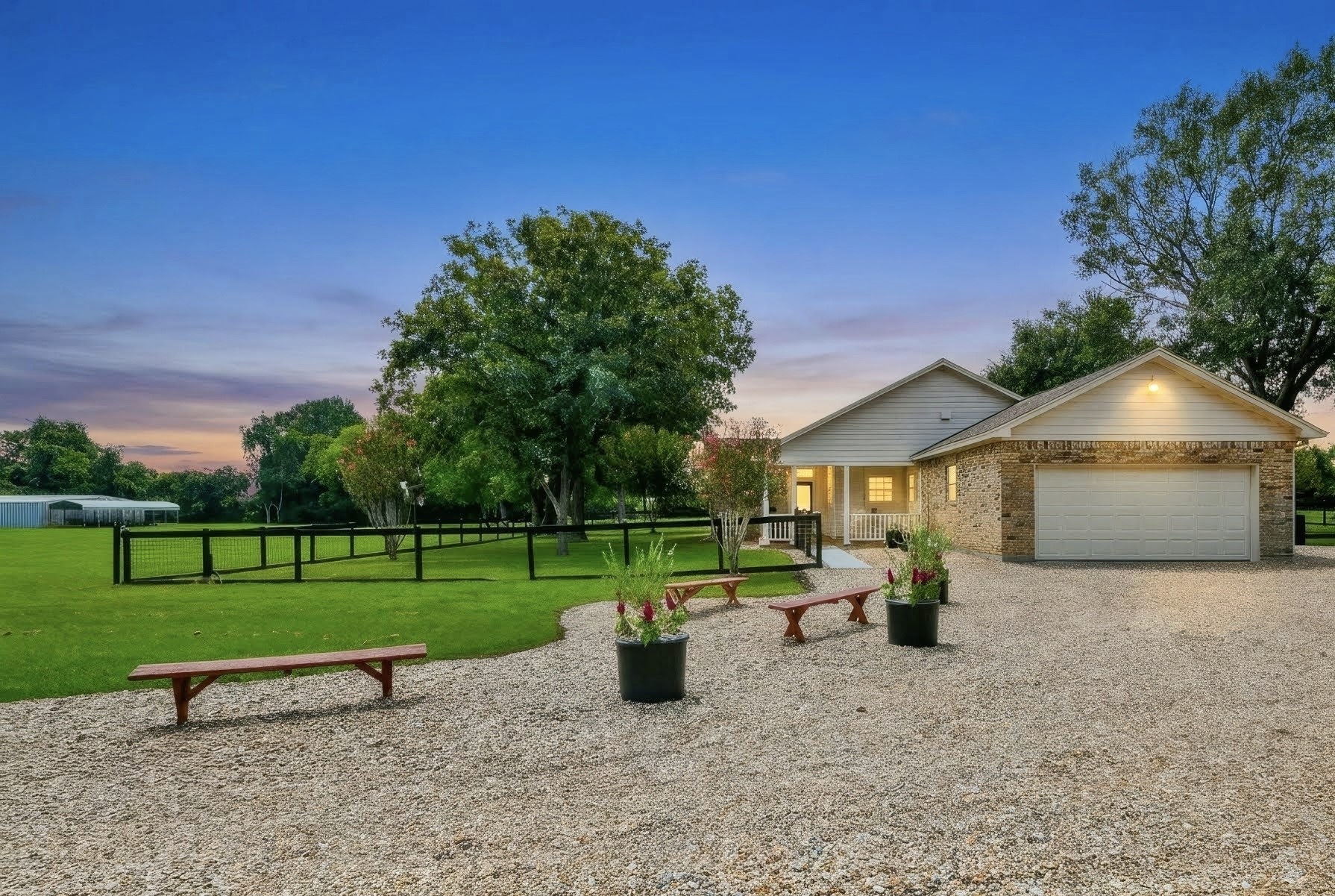 New gravel driveway, primary house with huge porch, and a view of the building towards the front of the property