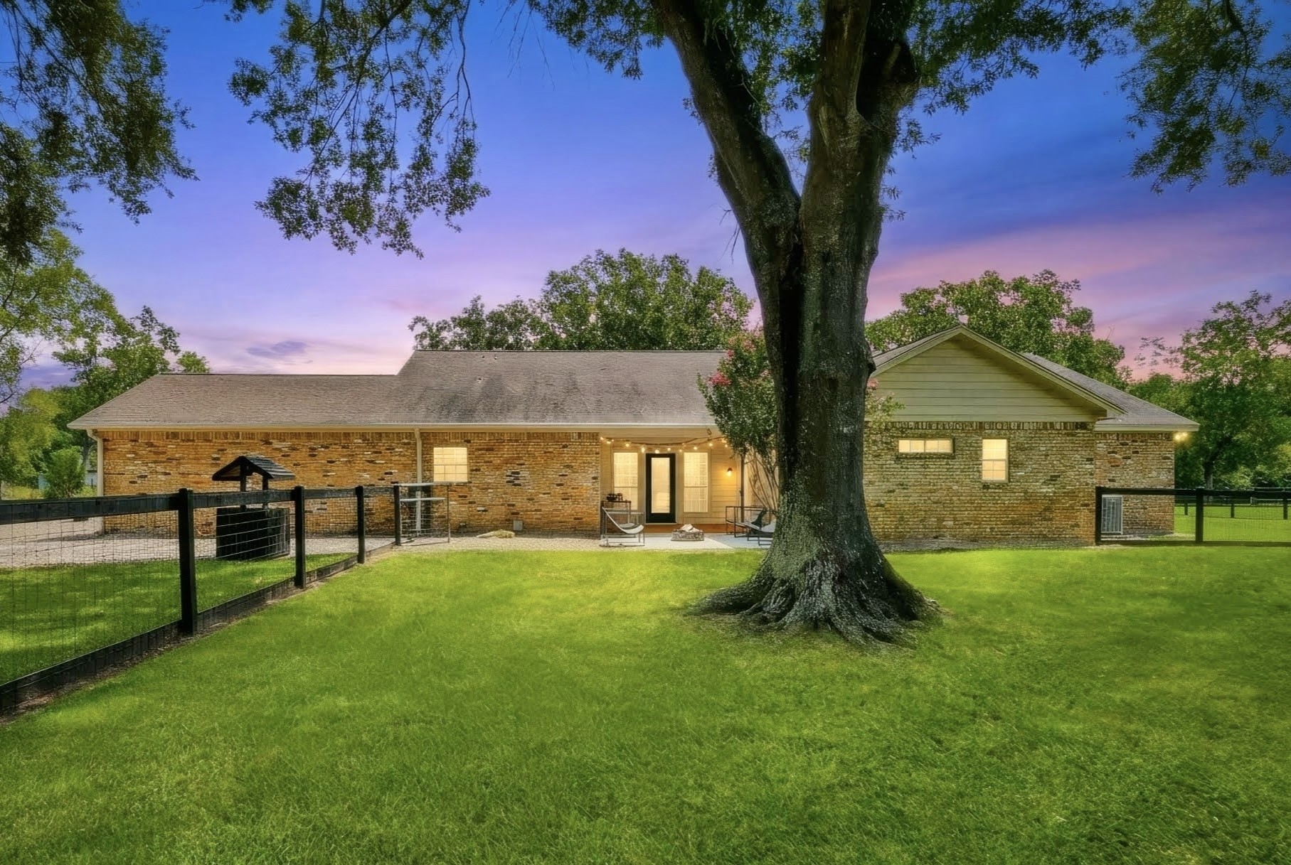 View of the primary house from the backyard featuring the covered rear porch and bricked firepit area