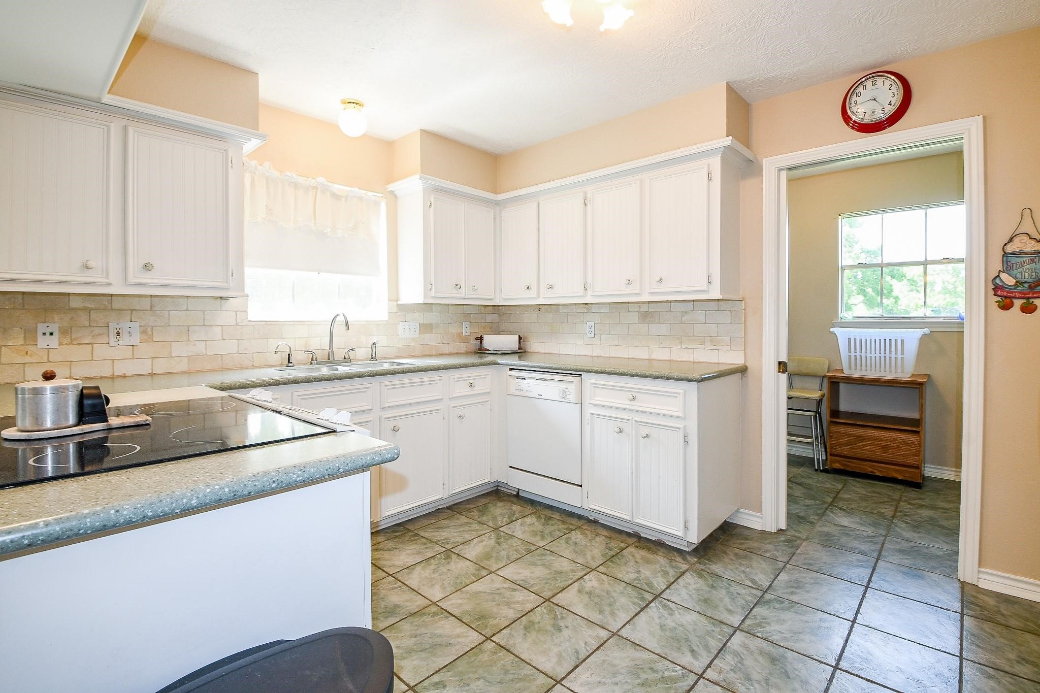 Large kitchen in the primary house with solid counters and white cabinets