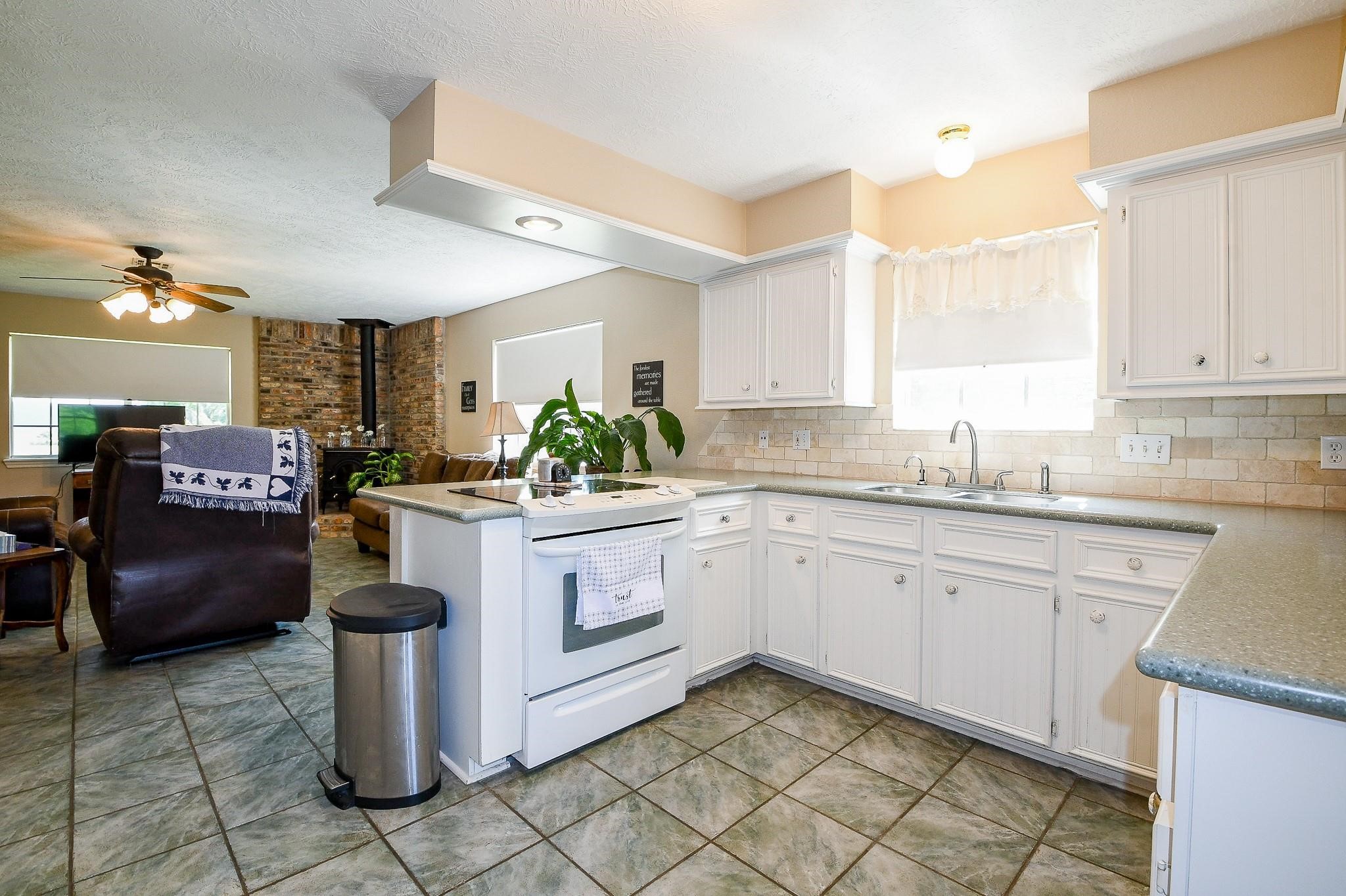 Large kitchen in the primary house with solid counters and white cabinets