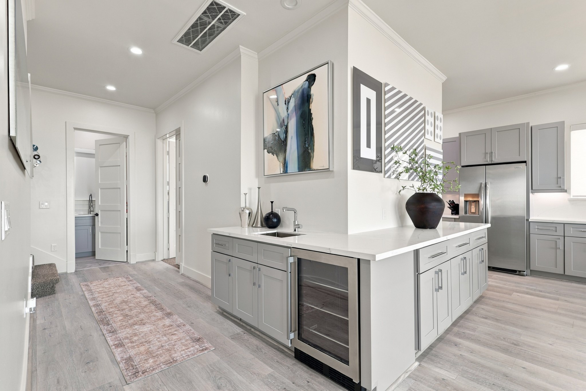 Entertain with ease at the centrally located wet bar, featuring a beverage refrigerator, prep sink, and generous cabinetry. Its convenient position beside the kitchen keeps refreshments close at hand.