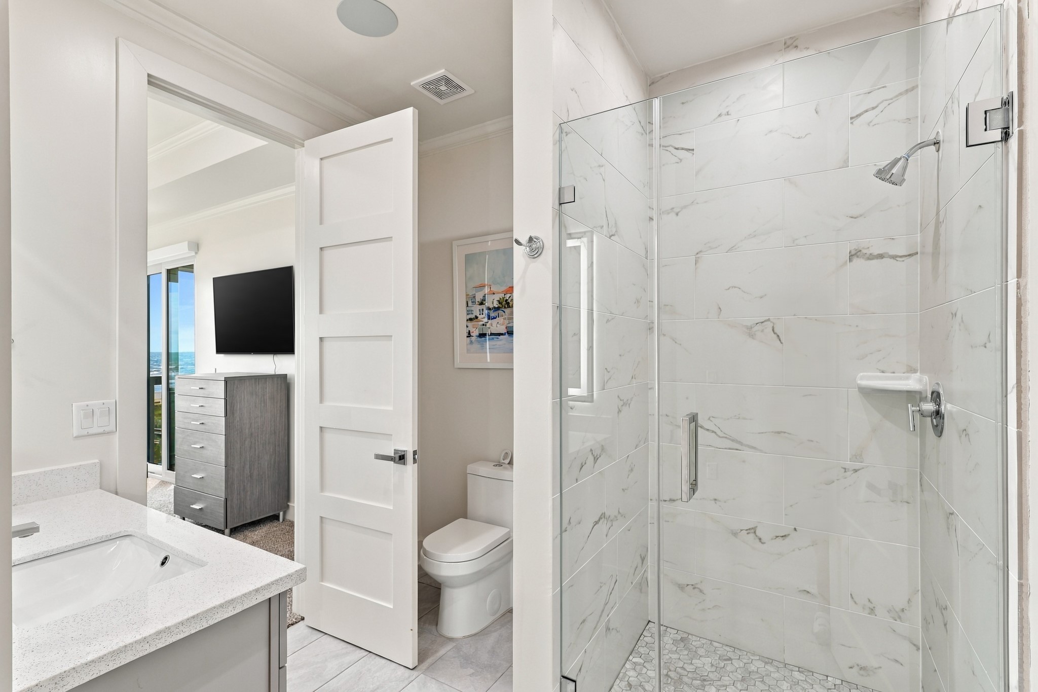 En suite bathroom
Contemporary en suite bathroom featuring a glass-enclosed walk-in shower, marble-look wall tile, and a mosaic shower floor. Direct bedroom access adds everyday convenience.