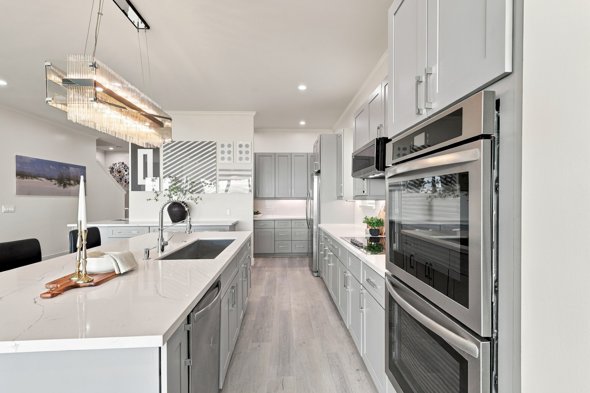 Double wall ovens, generous island workspace, and abundant cabinetry bring function to this elegant kitchen. Subtle countertop veining and a statement light fixture complete the polished look.