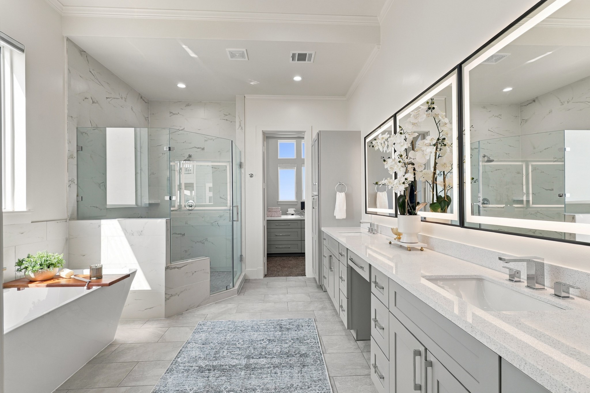 Primary bathroom
An expansive primary bathroom pairs a long dual-sink vanity with illuminated mirrors and generous cabinetry. A freestanding soaking tub and separate glass-enclosed shower create an elegant space to unwind.