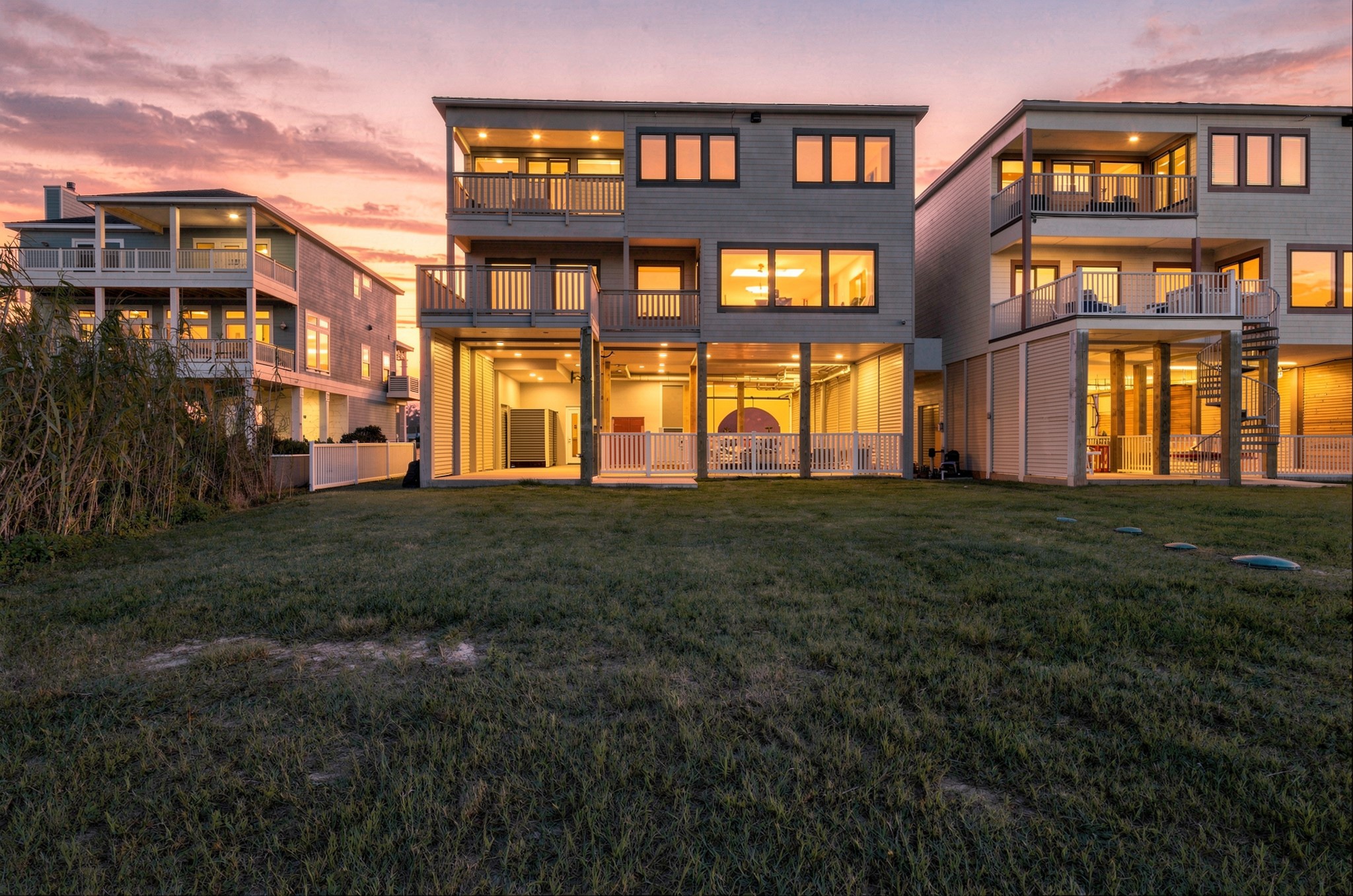 Beach-facing exterior at dusk
Warm evening lighting highlights the homes beach-facing elevation, covered balconies, and expansive windows. The lawn and sheltered ground-level spaces extend the opportunities for coastal outdoor living.