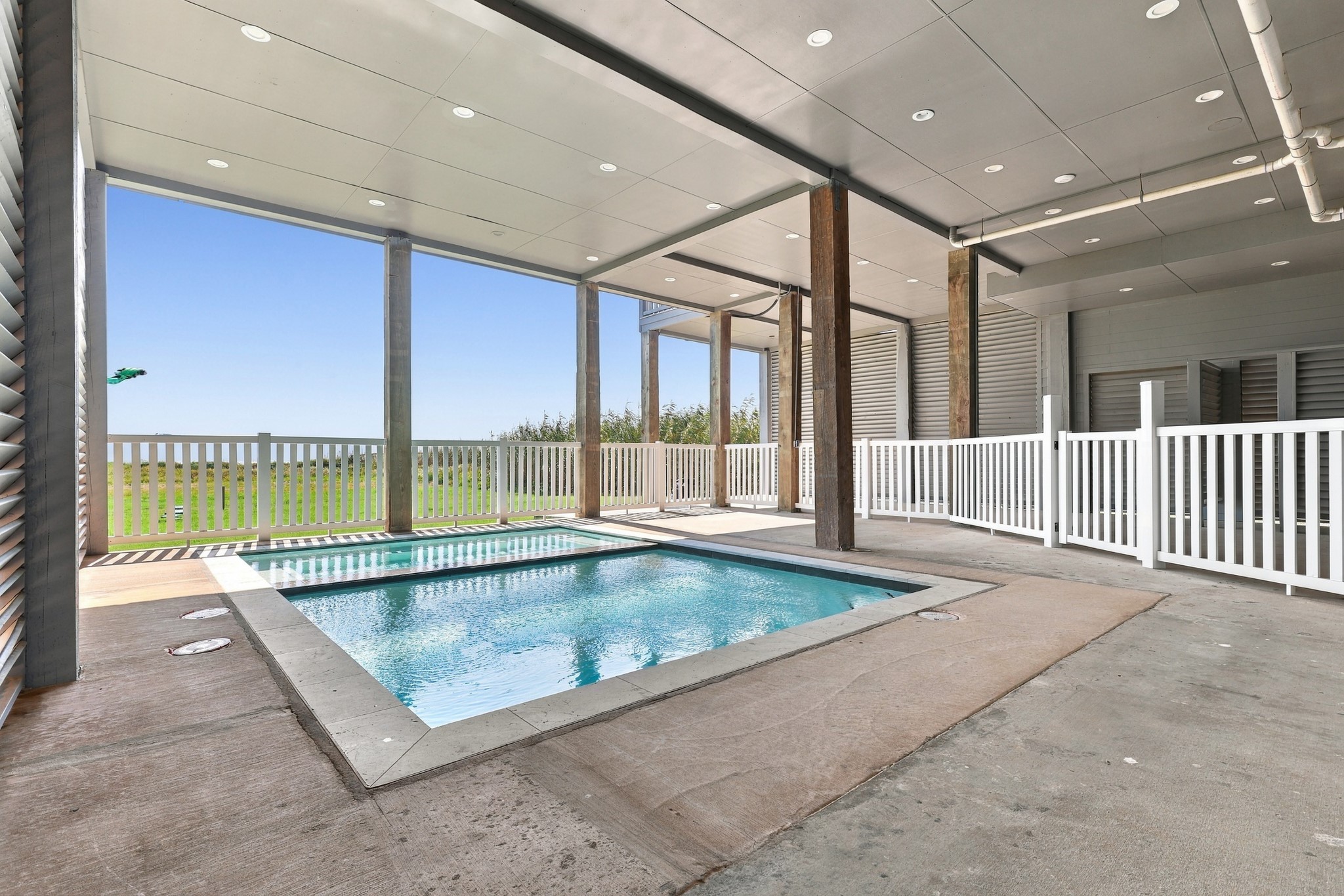 Pool area, alternate view
An alternate view showcases the pool and spa, surrounding deck space, and covered setting. White railings define the area while preserving views toward the coastal landscape.