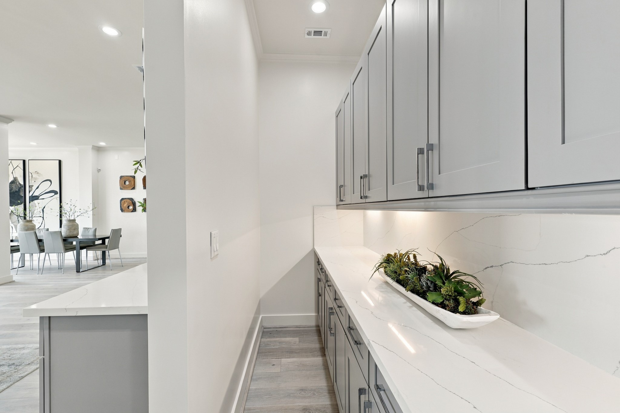 An extended counter and additional upper and lower cabinetry provide valuable storage and serving space, conveniently tucked alongside the main kitchen.
