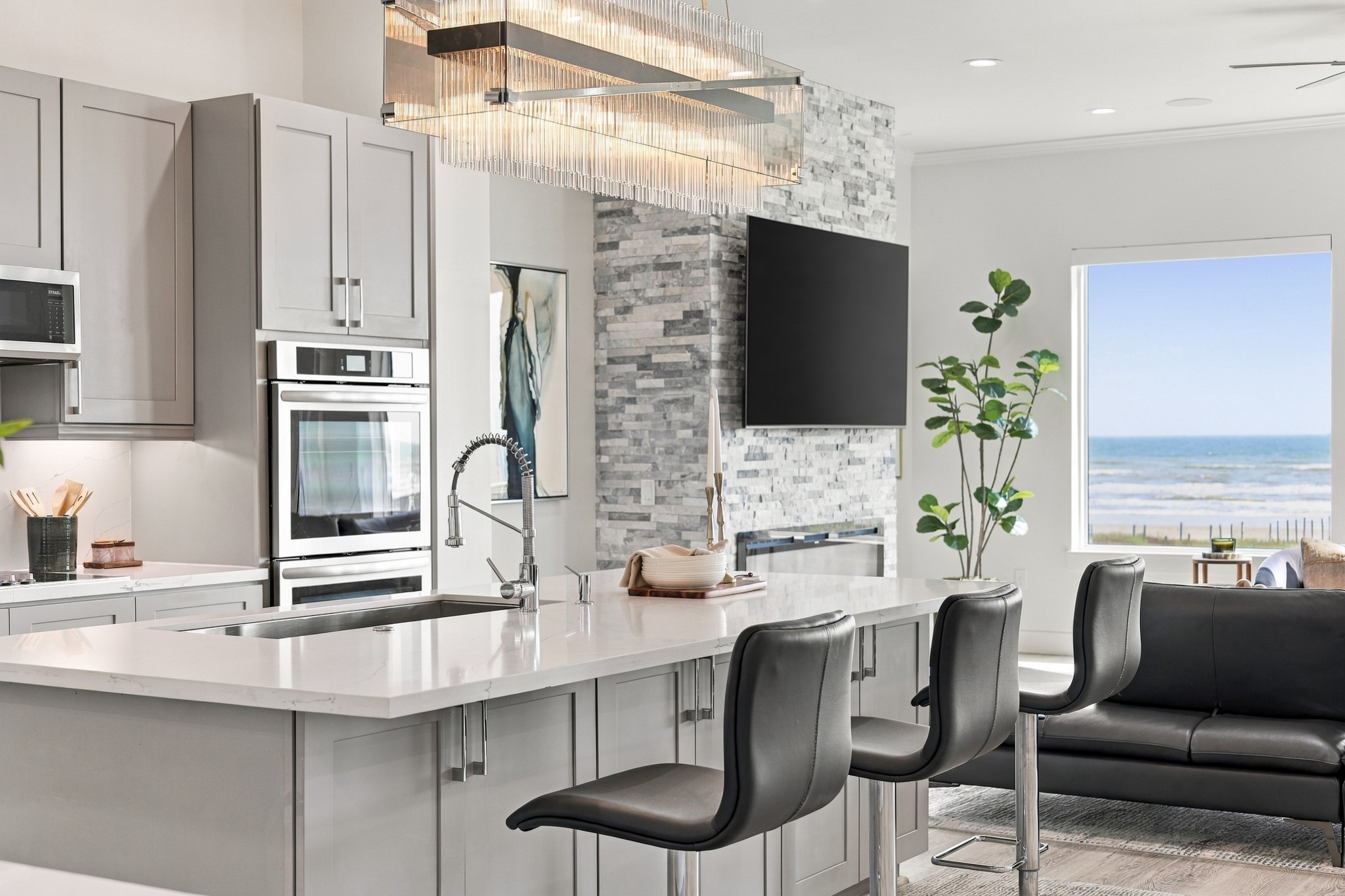 Kitchen and living detail
A generous island with breakfast-bar seating connects the kitchen to the Gulf-facing living room. Double wall ovens, gray cabinetry, and a statement chandelier balance everyday function with sophisticated style.