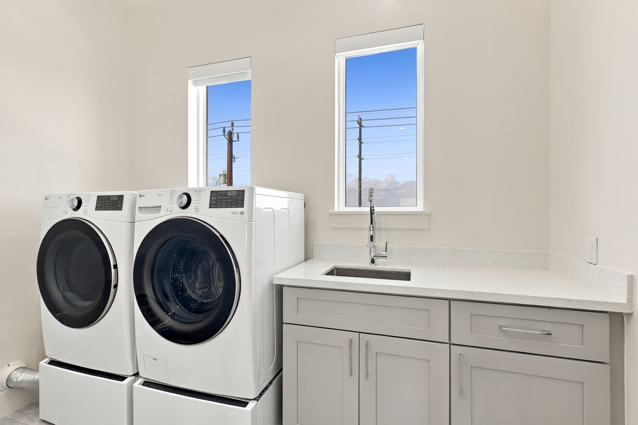 Bright laundry room with space for side-by-side appliances, a utility sink, and a broad folding counter. Lower cabinetry adds convenient storage for household essentials.