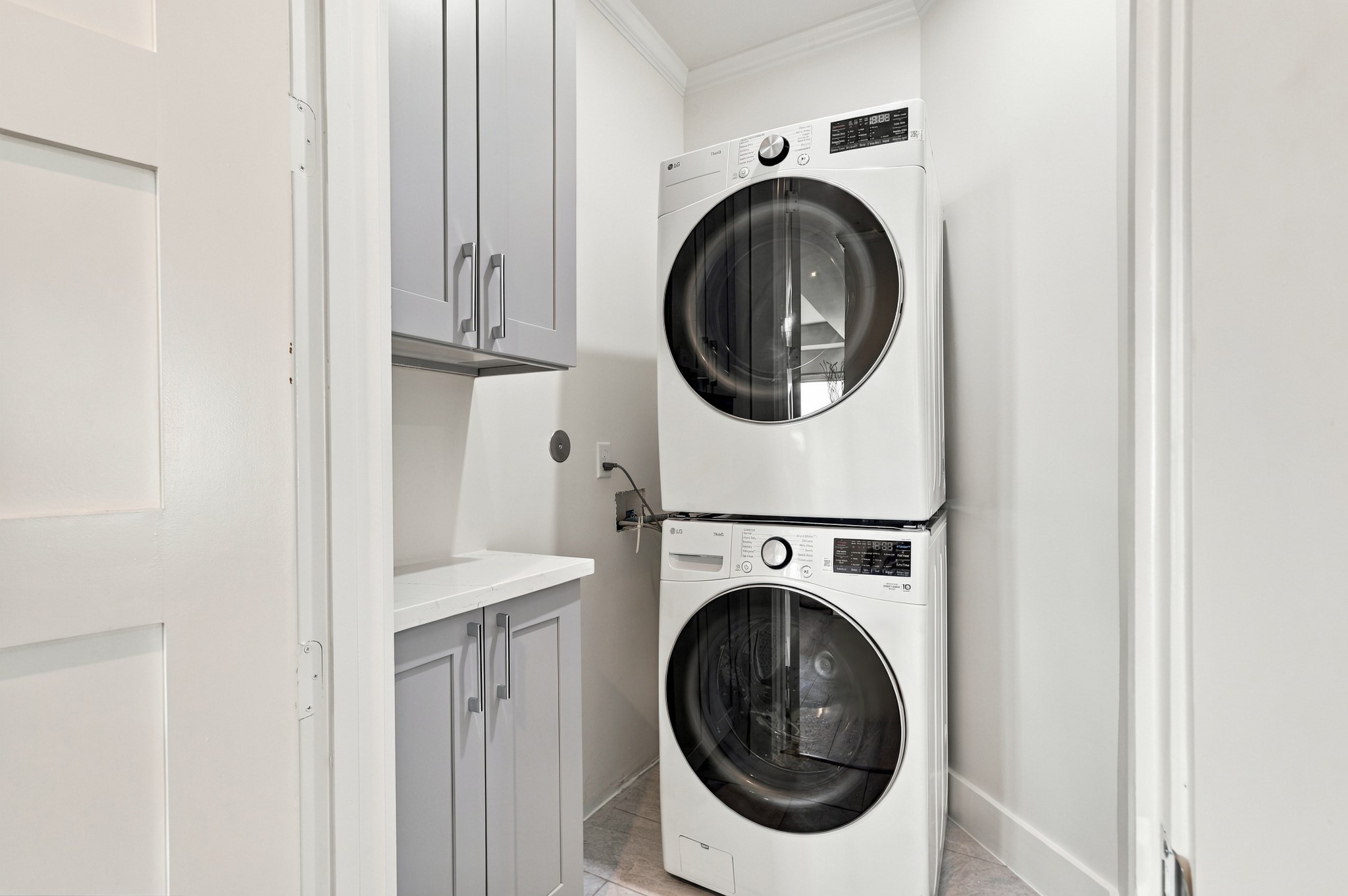 Additional laundry area
A second laundry area offers added convenience with stacked appliances, a compact counter, and upper and lower cabinetry. The efficient layout keeps everyday essentials neatly organized.