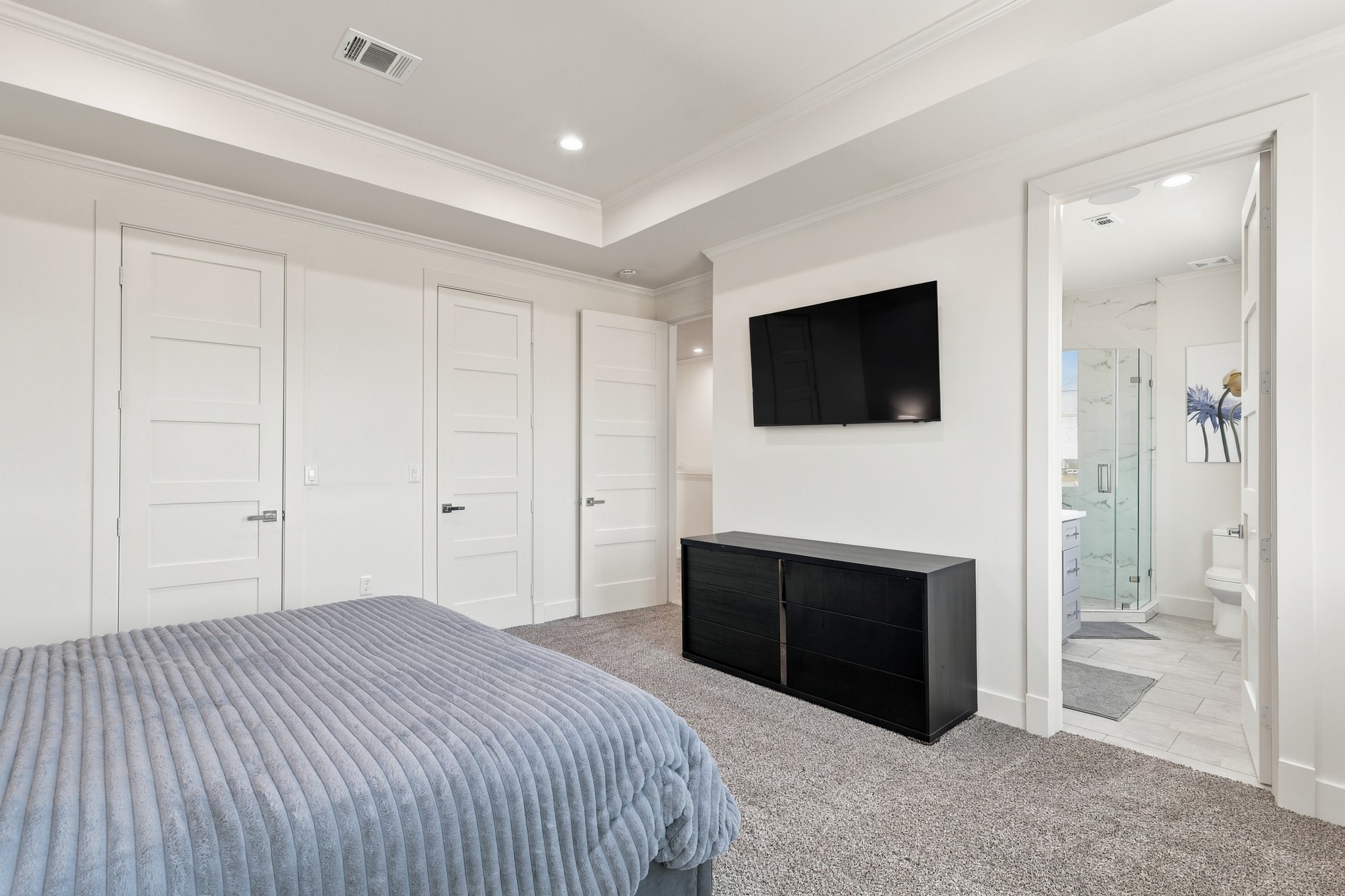Bedroom with adjoining bathroom
An alternate view showcases the bedrooms paneled doors, architectural ceiling detail, and direct access to an adjoining bathroom. A comfortable layout provides room for both sleeping and storage furnishings.