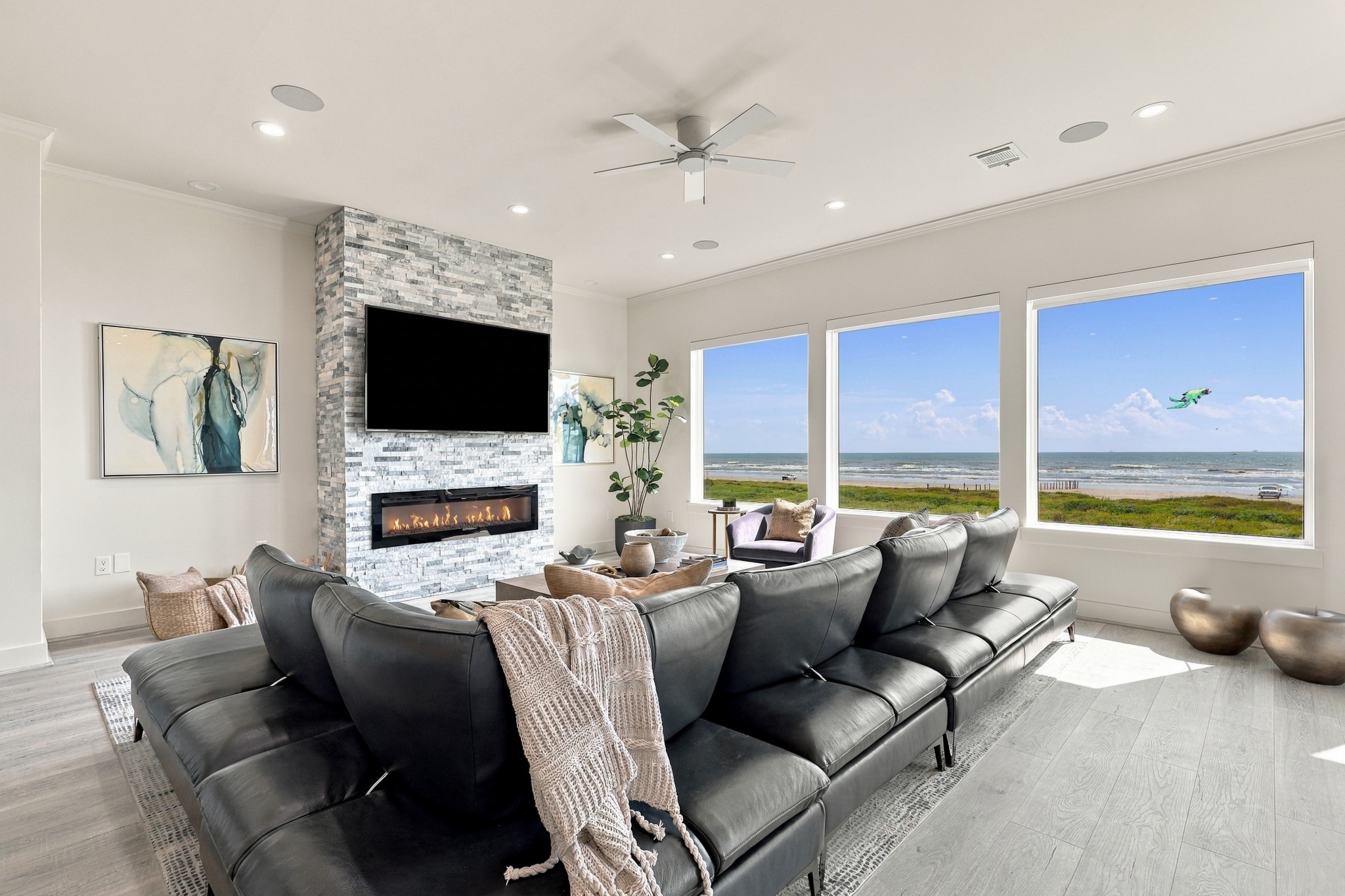 Broad picture windows frame the beach and Gulf, creating a stunning backdrop for everyday living. A stacked-stone fireplace surround adds texture and warmth to the contemporary interior.