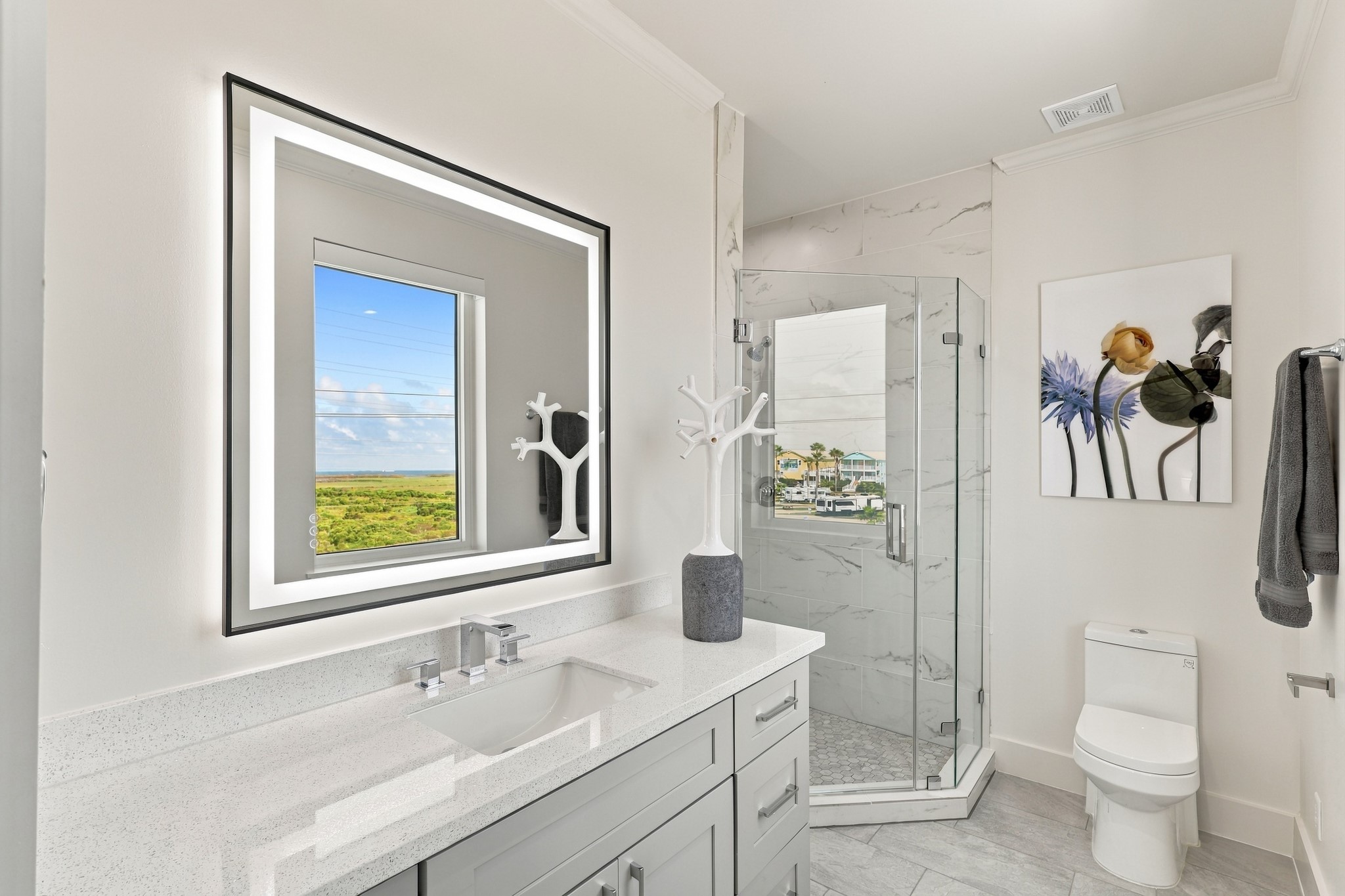 Full bathroom
Refined bathroom featuring a glass-enclosed walk-in shower, marble-look tile, and a generous gray vanity. An illuminated mirror and natural light enhance the bright, contemporary finish.