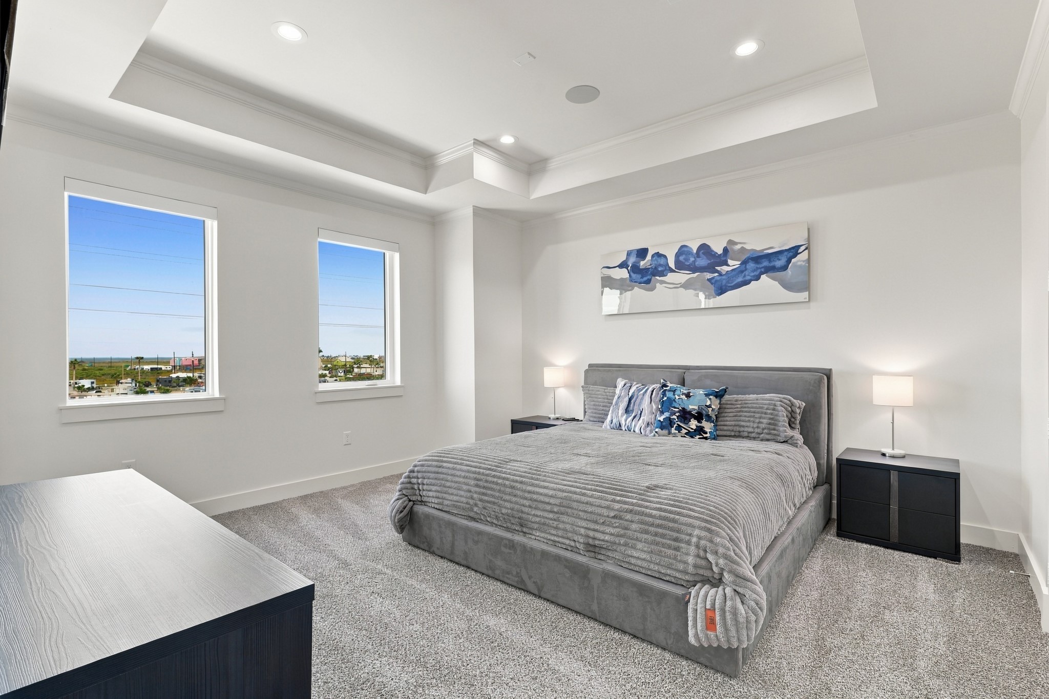 Third bedroom
A spacious secondary bedroom featuring a distinctive tray ceiling, soft carpeting, and two tall windows. Natural light and understated finishes create a restful coastal retreat.
