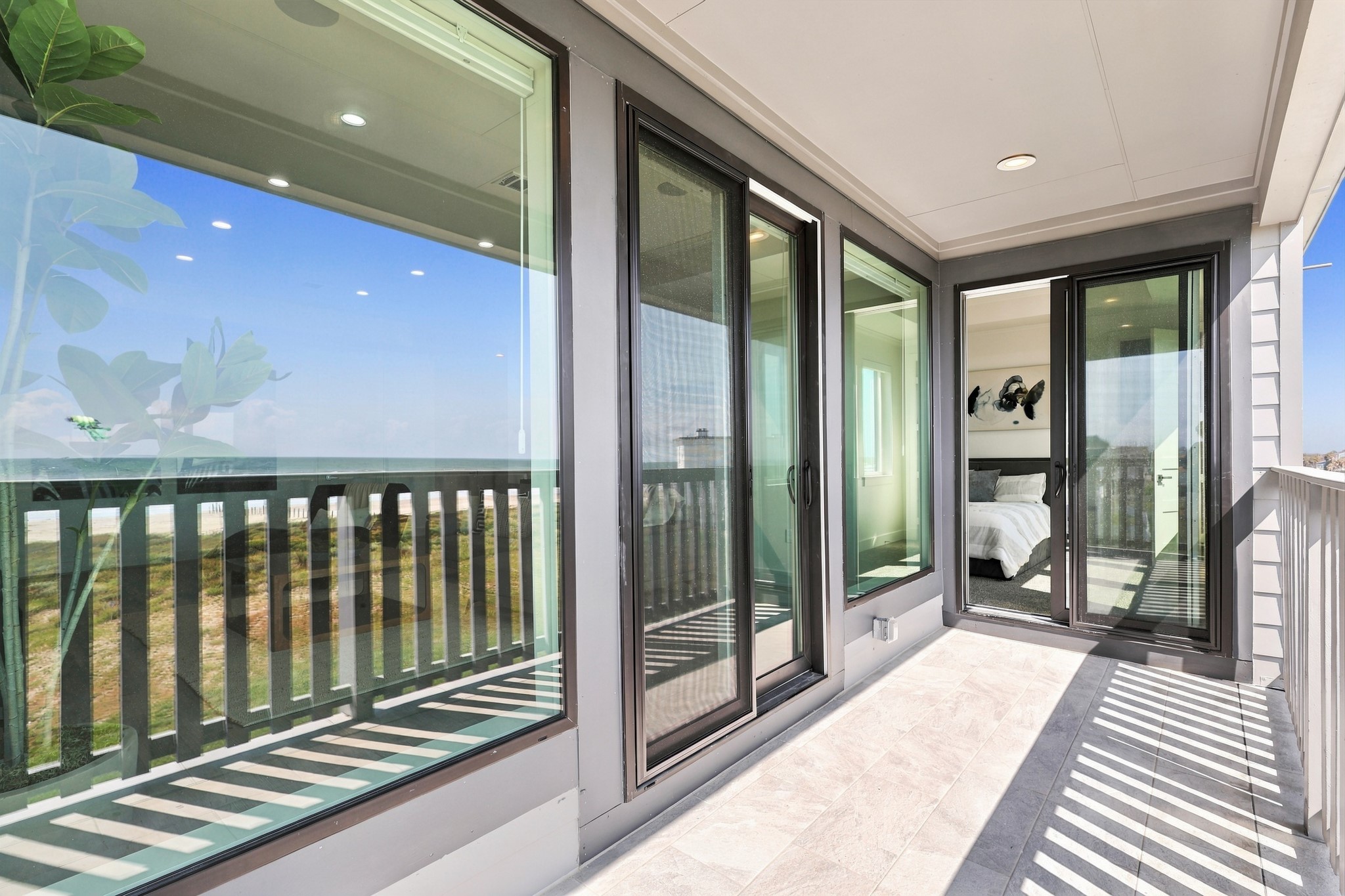 Bedroom balcony access
Sliding glass doors connect the bedroom to a covered Gulf-facing balcony. Large windows reflect the coastal scenery and carry natural light into the adjoining interior.
