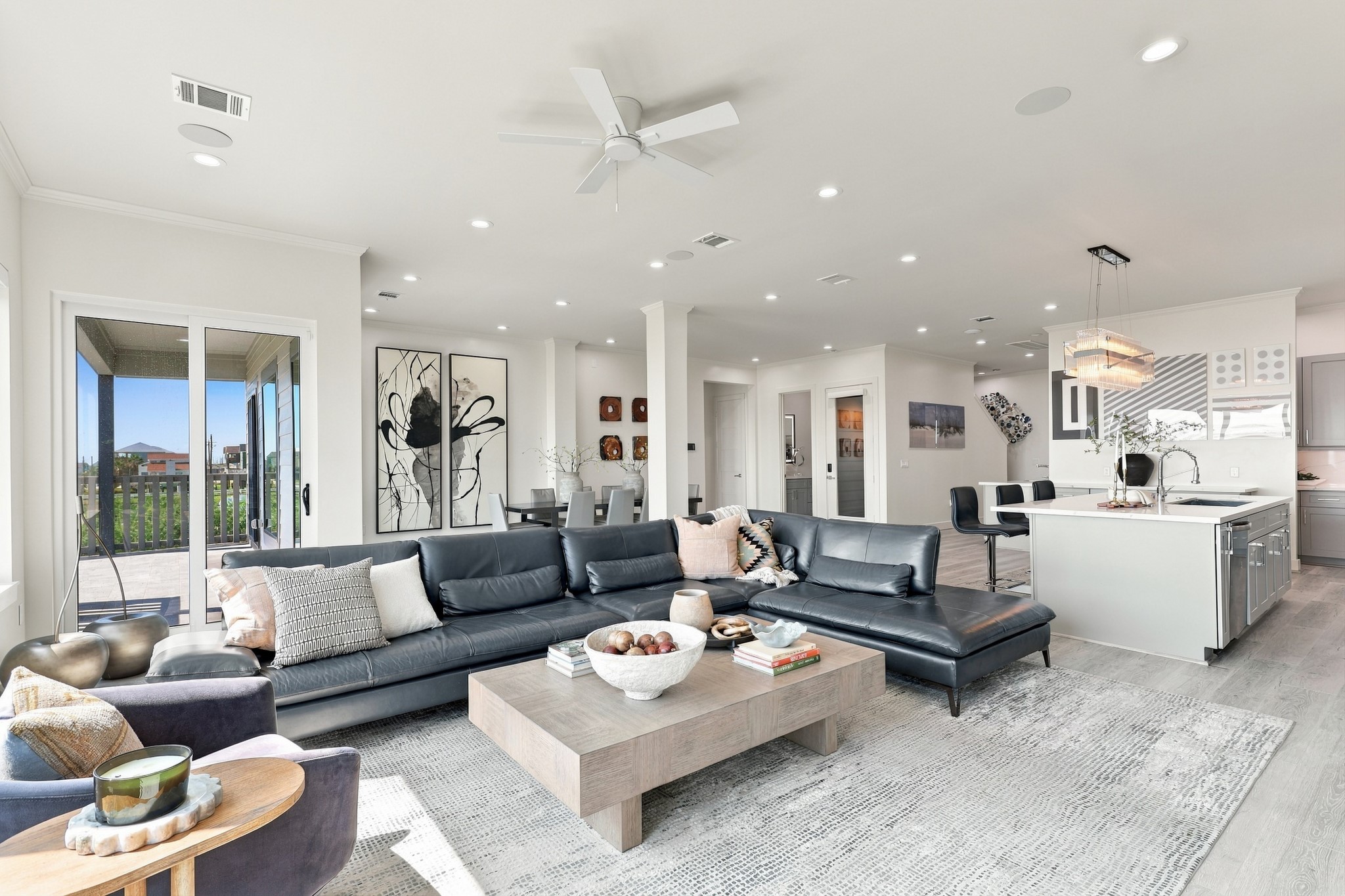 An inviting gathering space connects seamlessly to the island kitchen and dining area. Sliding glass doors open to the covered deck for easy indoor-outdoor entertaining.
