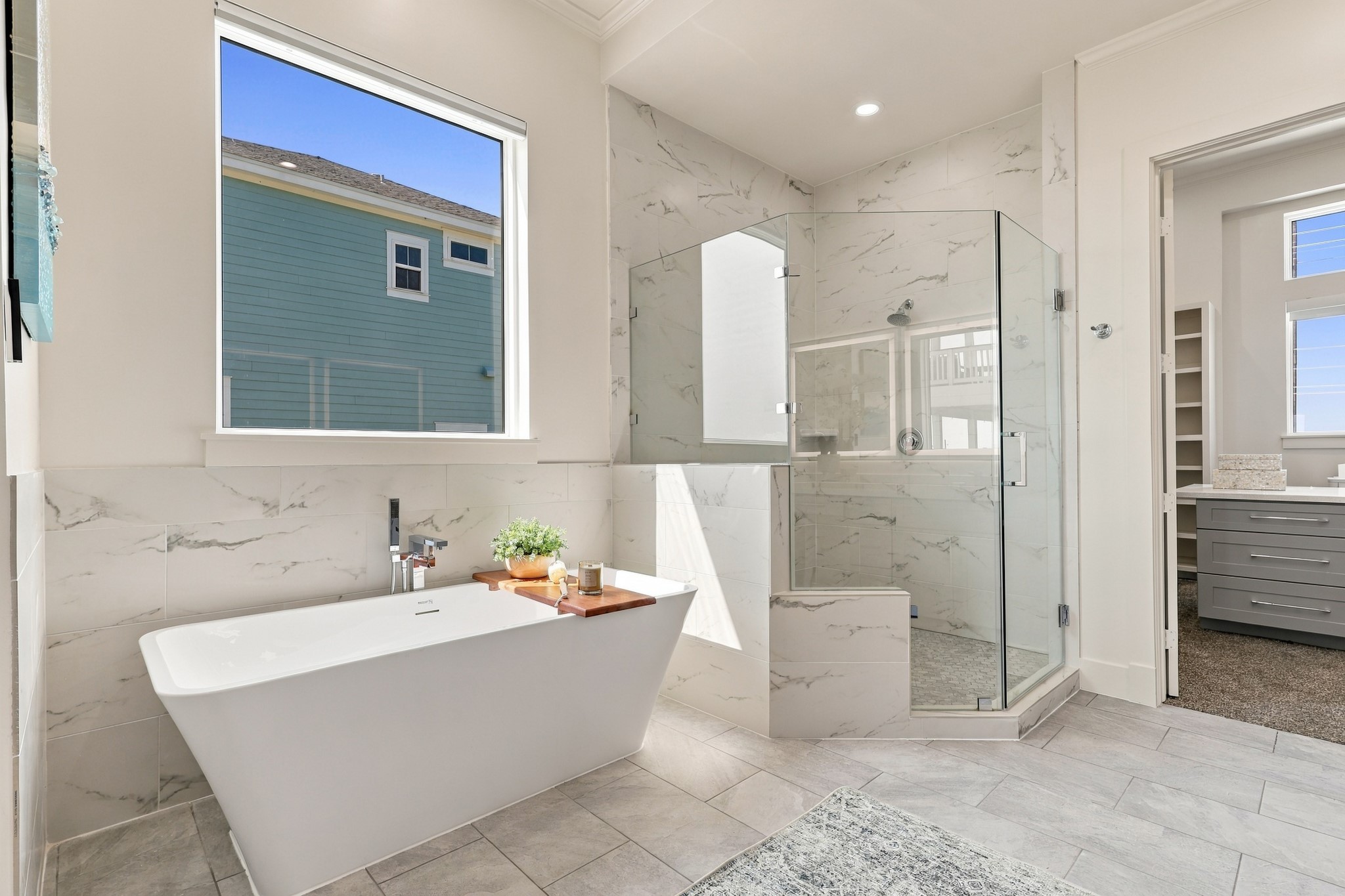 Soaking tub and shower
A sculptural freestanding tub sits beneath a large window beside the glass-enclosed shower. Coordinating marble-look tile brings a refined, cohesive finish to this relaxing retreat