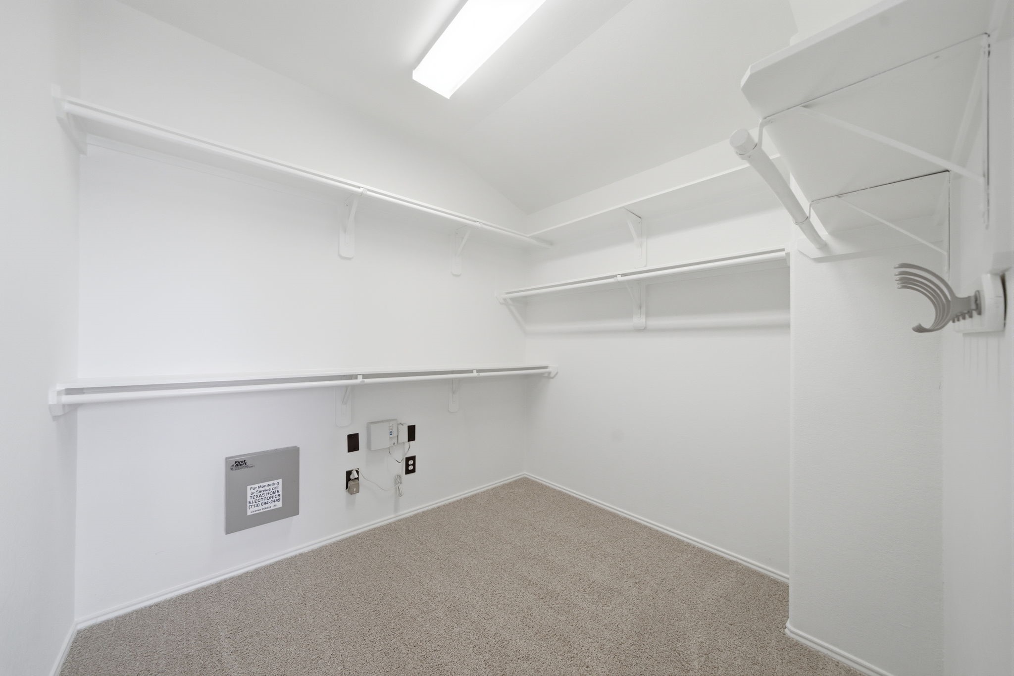 Extensive multi-level shelving and hanging rods maximize every inch of this primary suite's expansive walk-in closet. Soft carpet flooring and bright white finishes complete the functional storage space.