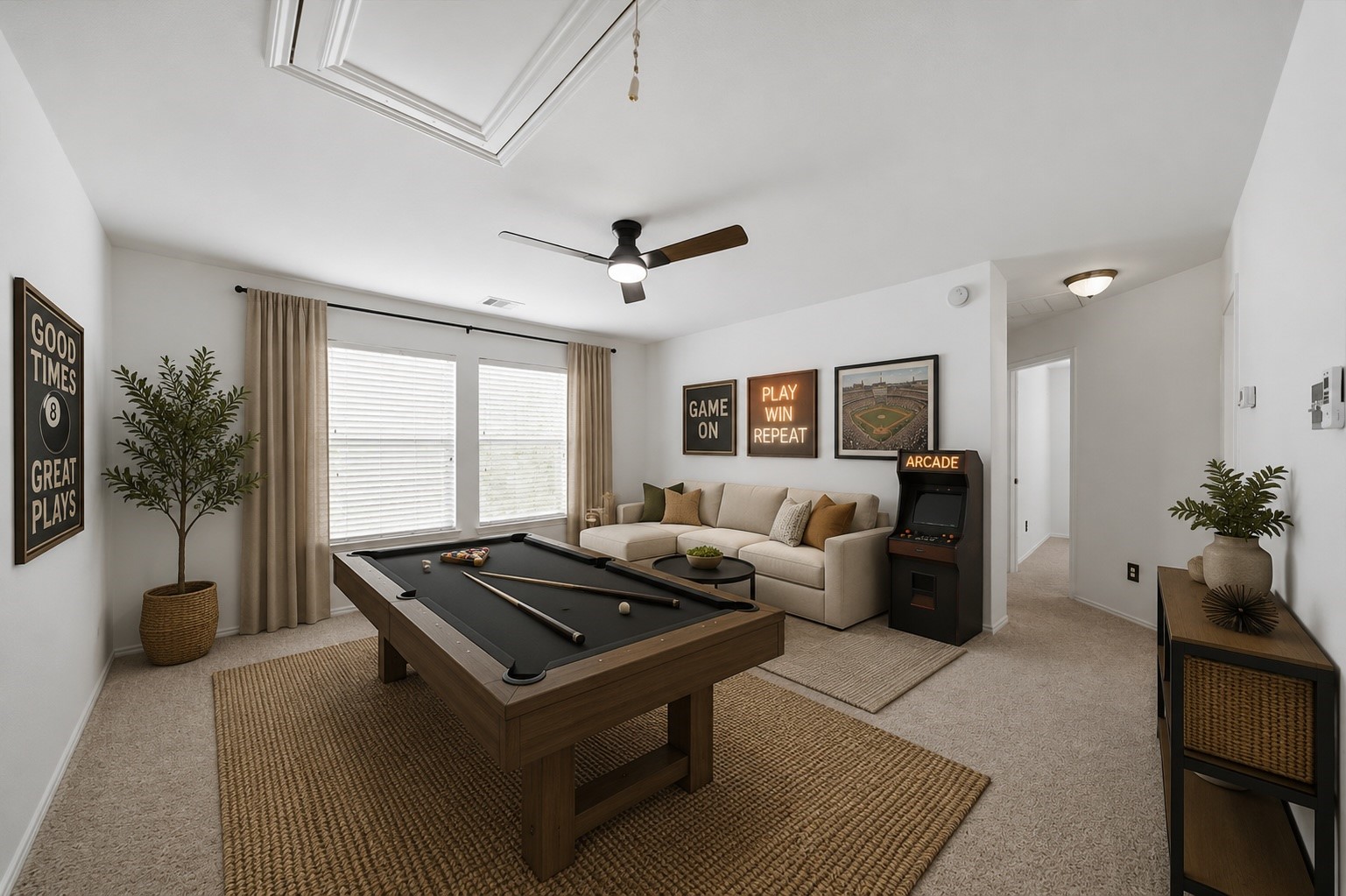 Soft carpet flooring and a central ceiling fan define this spacious second-floor gameroom. Dual windows stream natural light into the versatile space, offering generous room for a pool table, entertainment center, or creative play area. This photo has been virtually staged.