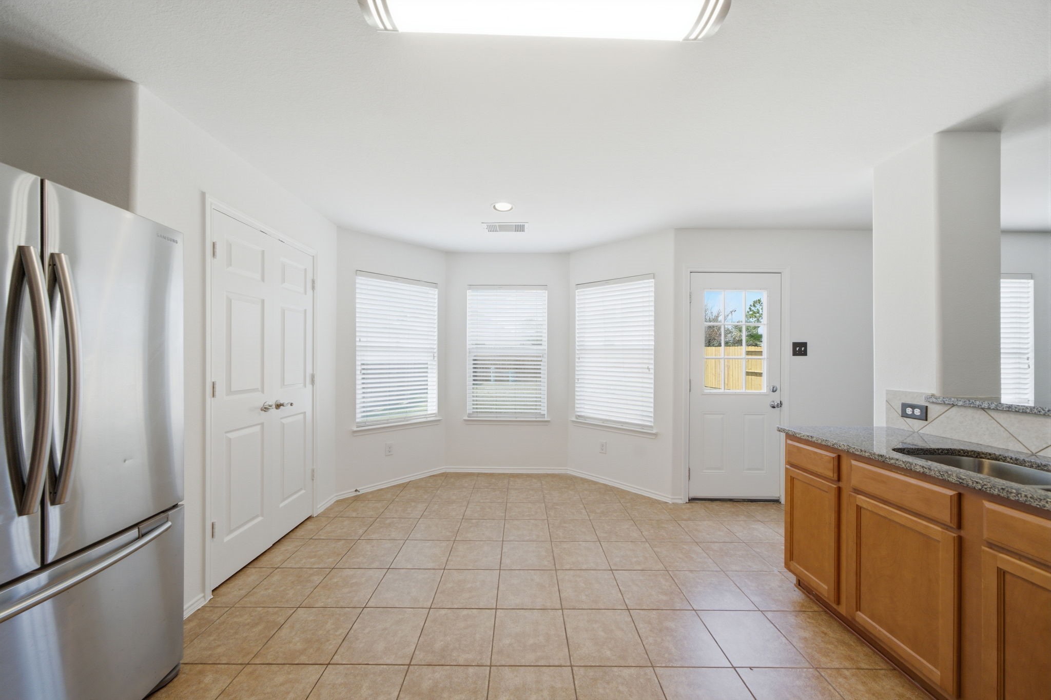 Bay windows illuminate this spacious breakfast area, complete with easy-care tile flooring and direct access to the private yard. Situated next to the kitchen, the open space accommodates daily meals with ease.