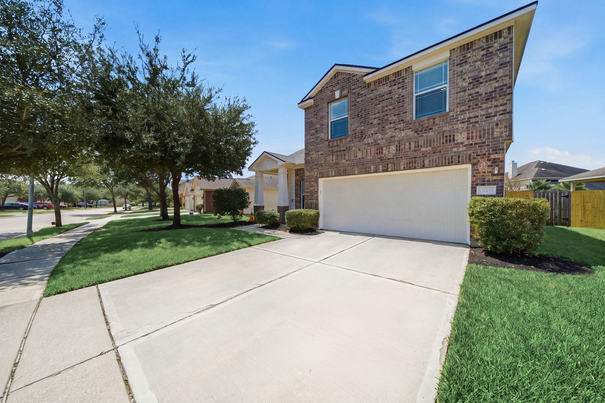 An expansive double-wide driveway leads to the 2-car garage and attached brick facade of this two-story home.