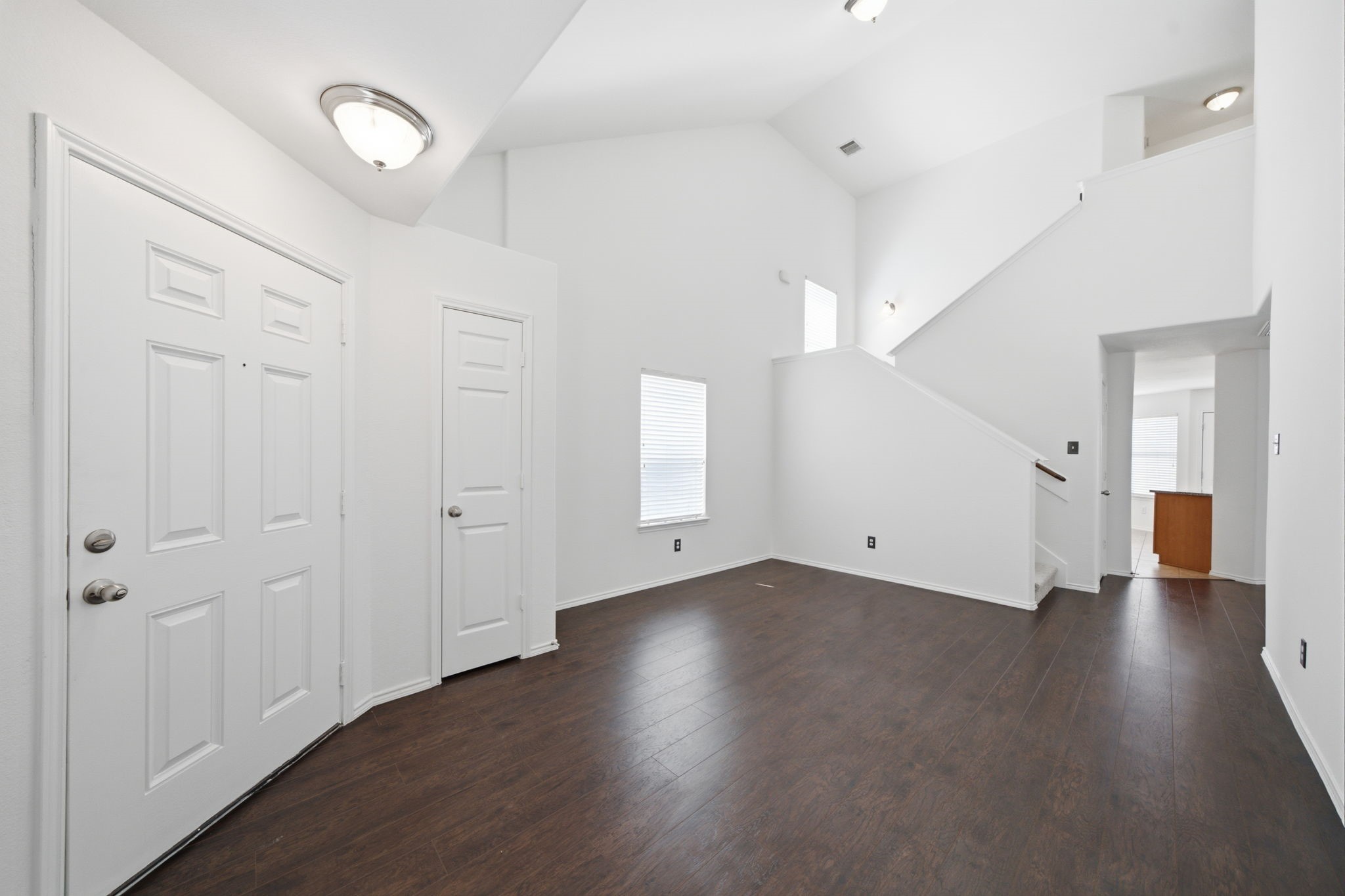 Soaring vaulted ceilings and rich wood-look flooring extend throughout this versatile formal dining space. Positioned steps from the entryway, the generous layout connects seamlessly toward the main living area and kitchen.