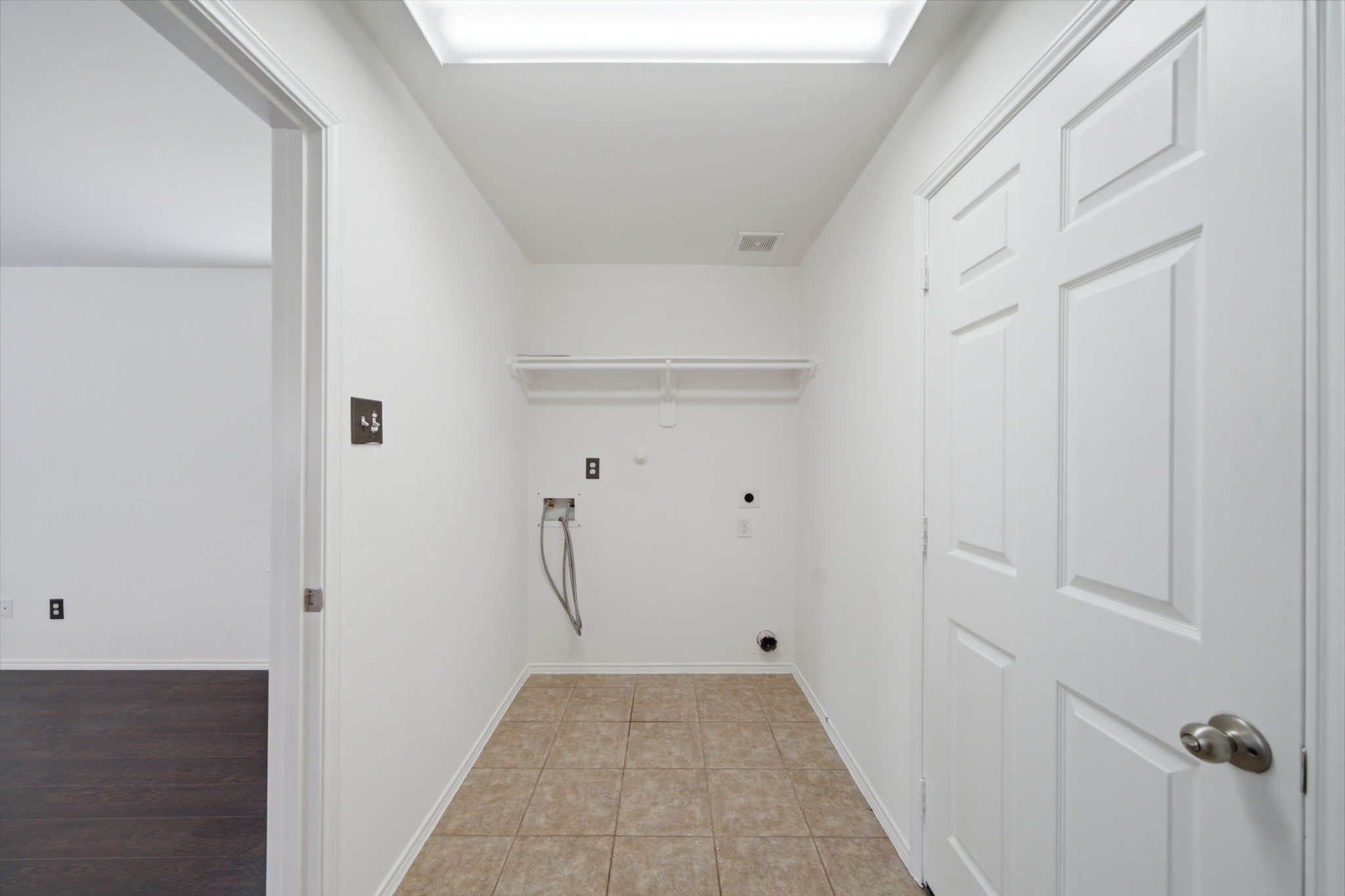 Durable tile flooring and overhead wire shelving define this dedicated utility room, offering convenient washer and dryer hookups.