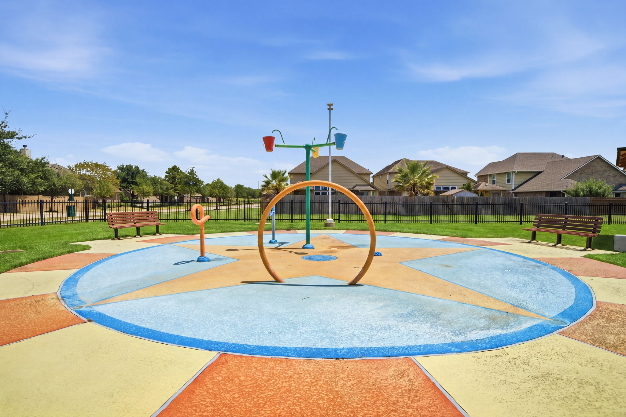 Bright star-patterned concrete paving anchors this neighborhood splash pad, featuring fun water features and surrounding park benches.
