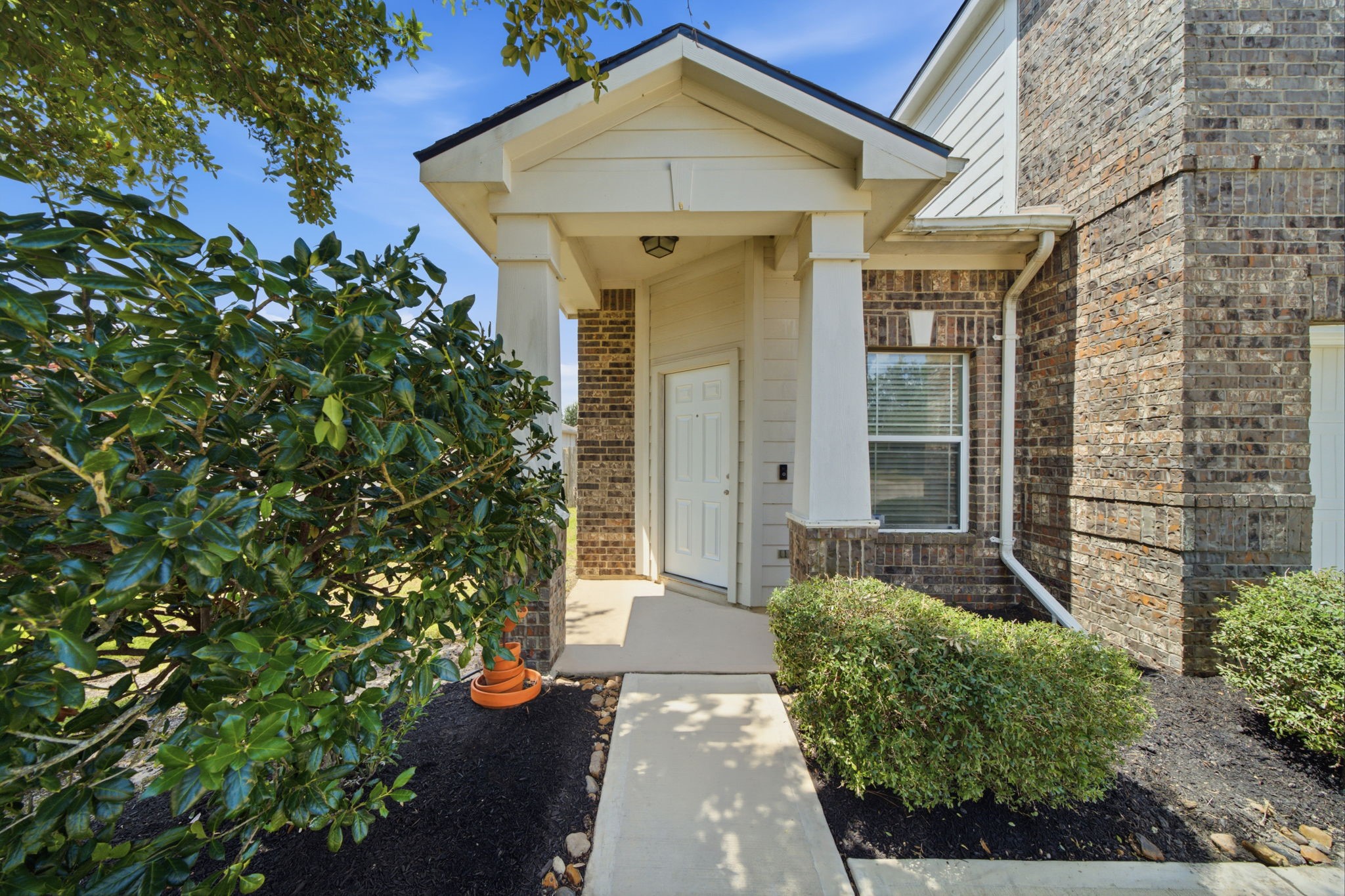 A covered entryway with handsome square columns and crisp trim highlights the classic brick facade, creating an inviting approach to the front door.