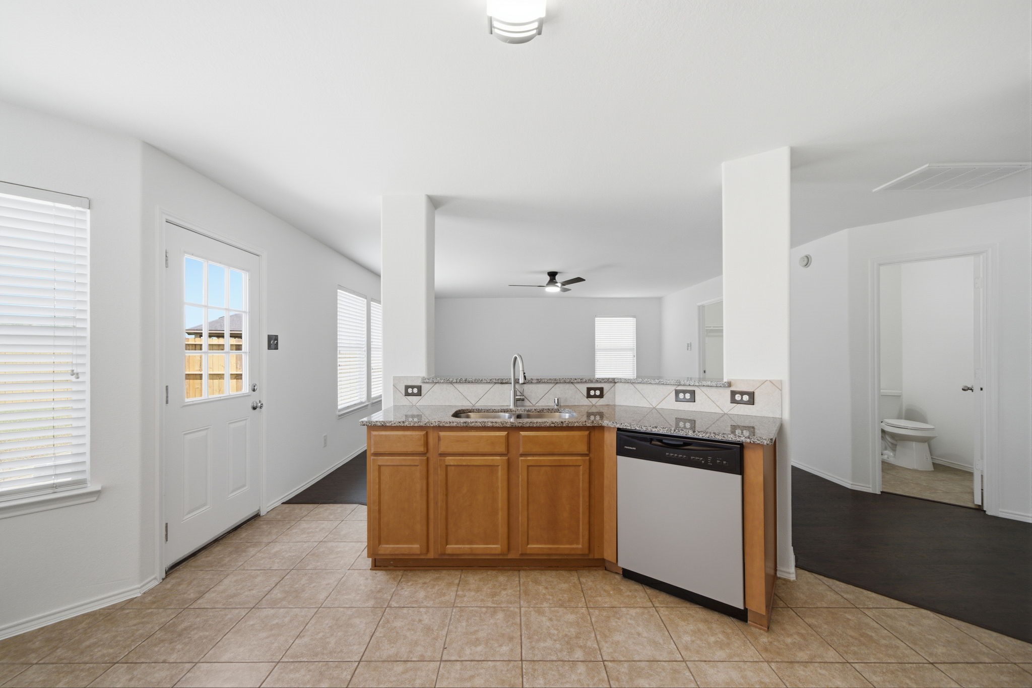 Featuring durable tile flooring and warm wood cabinetry, this updated kitchen offers granite countertops and a raised breakfast bar for casual dining. Raised bar seating creates seamless sightlines into the main living areas while providing convenient proximity to the adjacent half bath and exterior exit.